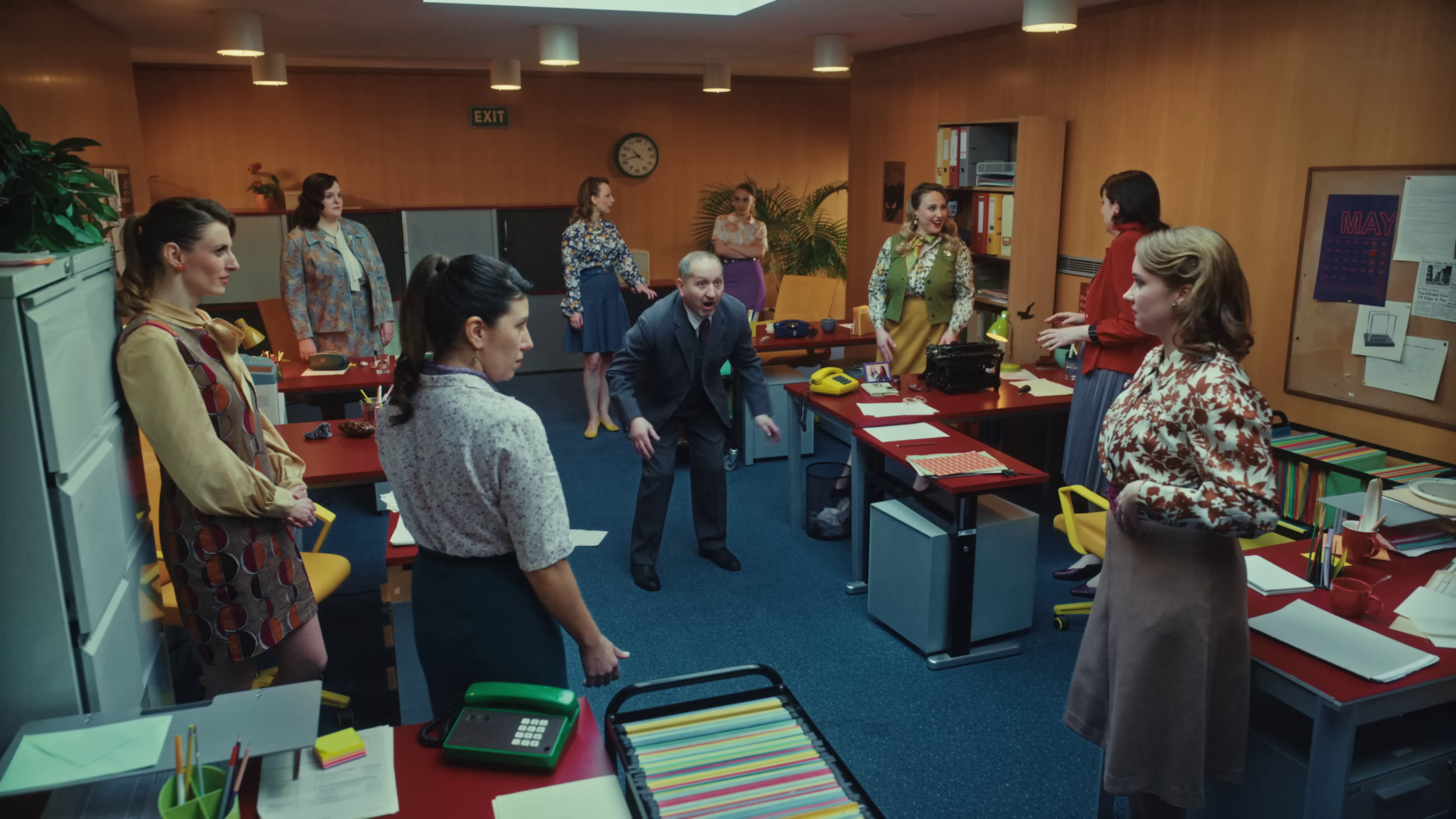 wide shot of the room, with several women watching a man dance