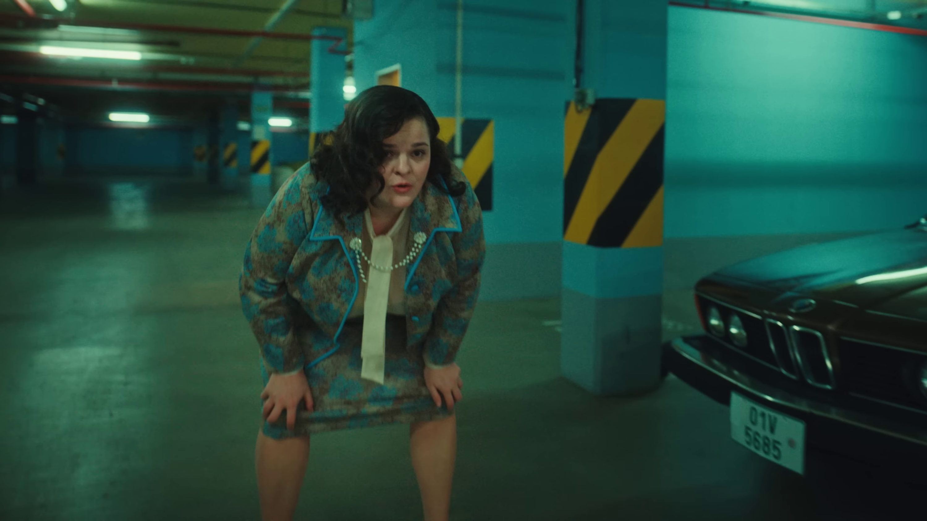 image of a woman in a blue suit bending over to catch her breath and looking offscreen