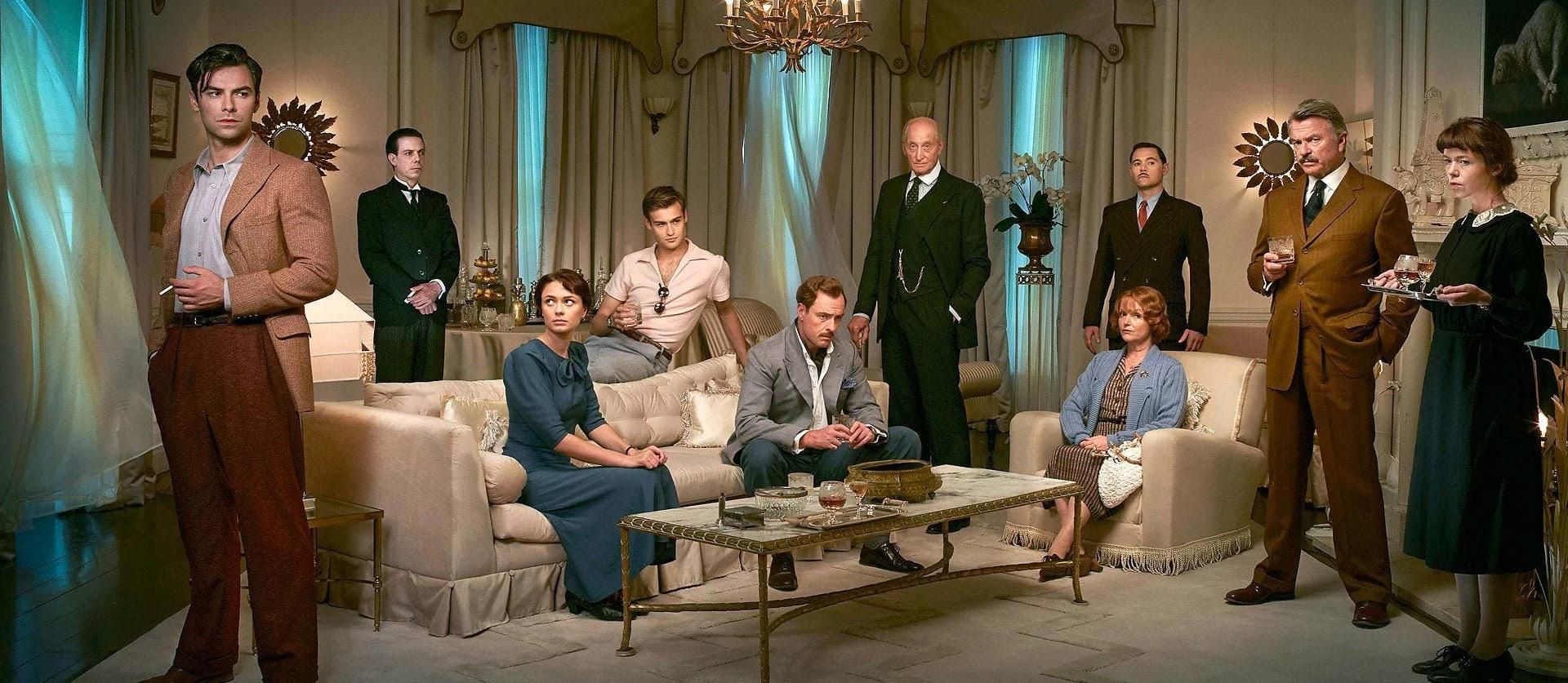 the cast of the 2015 BBC miniseries And Then There Were None, in costume, standing in a dining room or seated at the table
