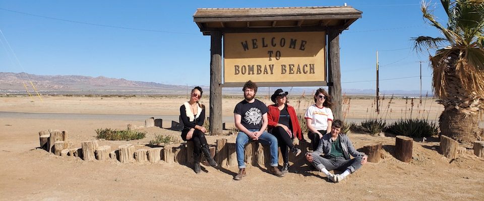 A group of people sitting in front of a sign Description automatically generated