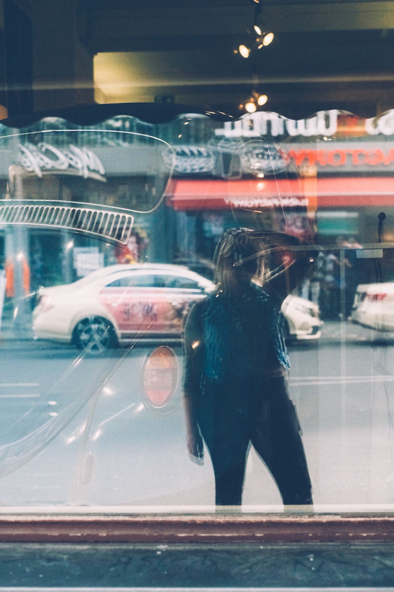 A self-portrait taken in a shop window on the street in Berlin, cars and storefronts in the background.
