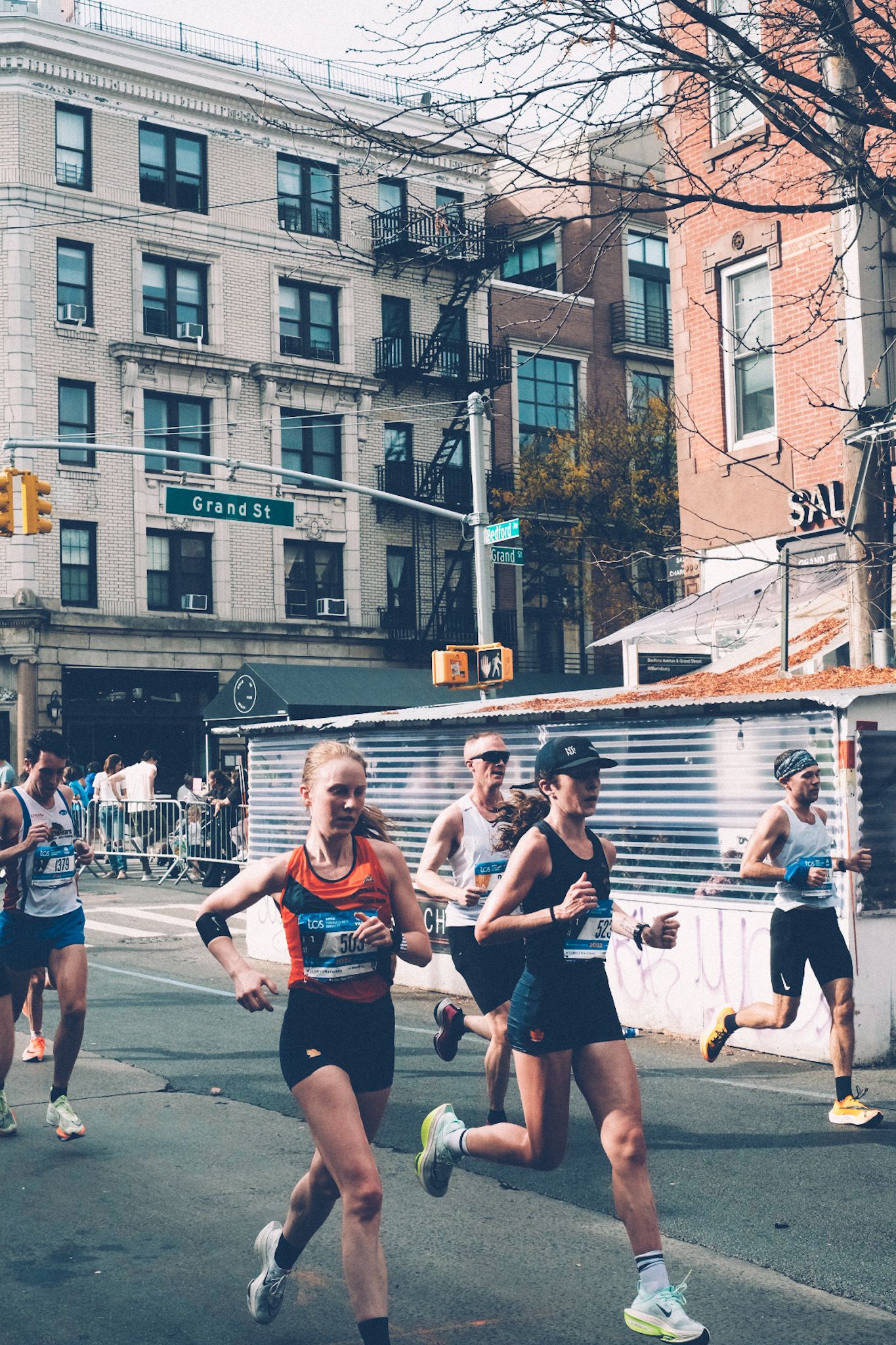 New York marathon runners run past on a city street.