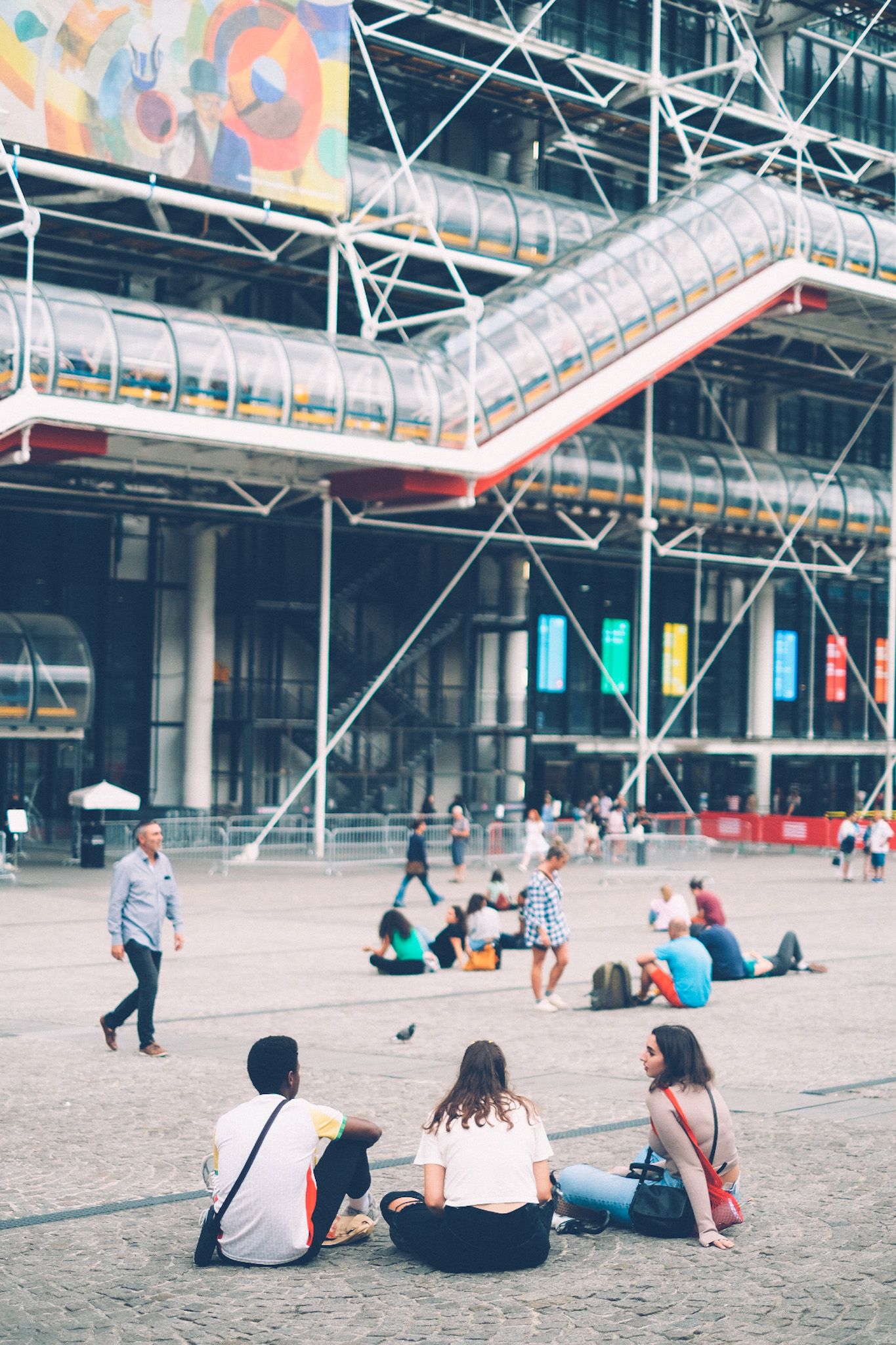 A trio of people sit on the ground outside of Paris�s Centre Pompidou.