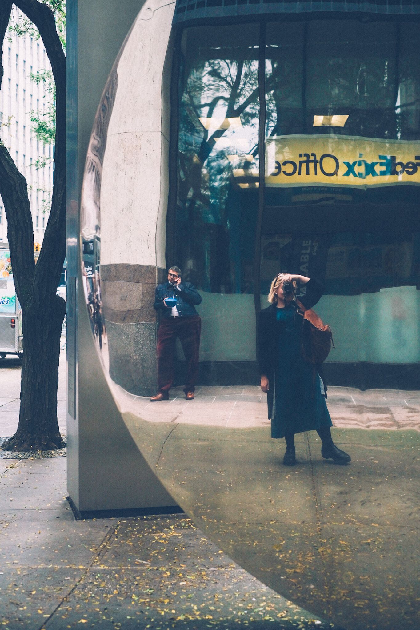 A woman takes a self portrait in a reflective sculpture in downtown New York.