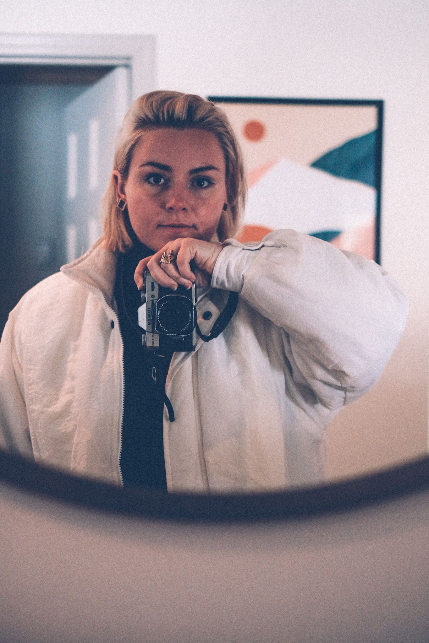 The author takes a self-portrait in a mirror, wearing a puffy white coat.