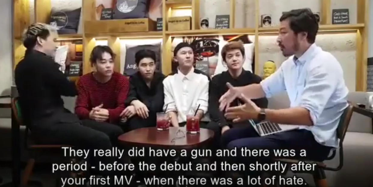 Image of an interviewer saying to Ninety One, “There really was a gun and there was a period, before the debut and then shortly after your first MV, where there was a lot of hate.”