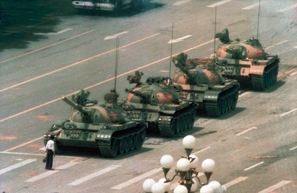 Man stands in front of column of tanks leaving Tiananmen Square