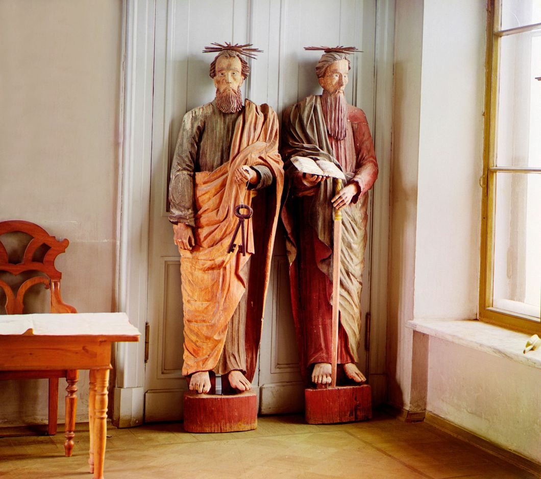 Two carved wooden statues of bearded men with a haloes above their heads, one holds a set of keys, the other a book