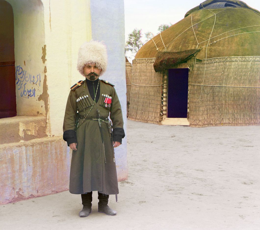 Man in uniform beside building, yurt in background