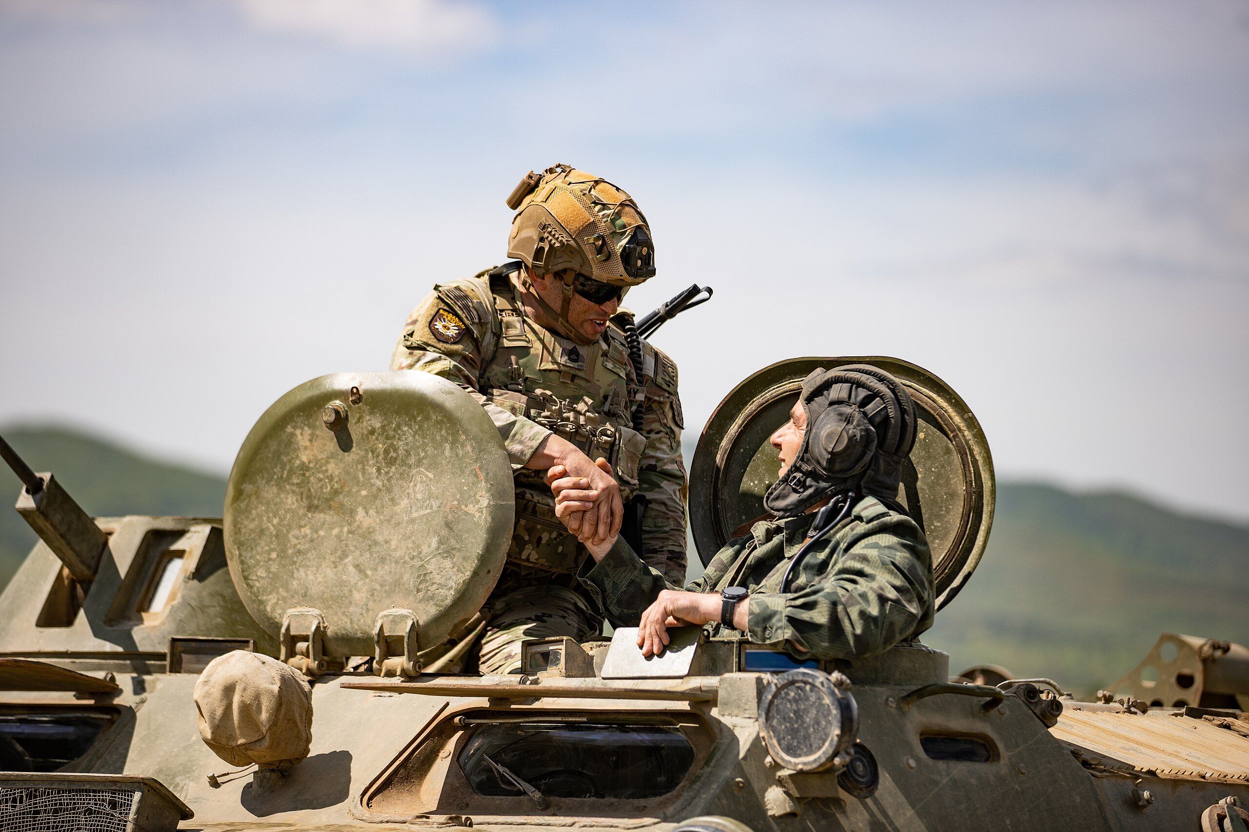 U.S. Army Sgt. 1st Class David Jones, operations advisor, 4th Security Force Assistance Brigade, shakes hands with Cpl. Stanimir Nenov, 42nd Mechanized Battalion, 2nd Mechanized Brigade, Bulgarian Land Forces, after a demonstration of capabilities at Bulgaria’s Armed Forces Day celebration, at Novo Selo Training Area, Bulgaria, May 6, 2022. The 4th SFAB partners with select NATO Allies and partner land forces to increase internal capability and interoperability in support of U.S. Army Europe and Africa security cooperation objectives. This provides USAREUR-AF the opportunity to improve combined force interoperability in an environment of mutual learning. (U.S. Army photo by Capt. Angelo Mejia, 5th Mobile Public Affairs Detachment)