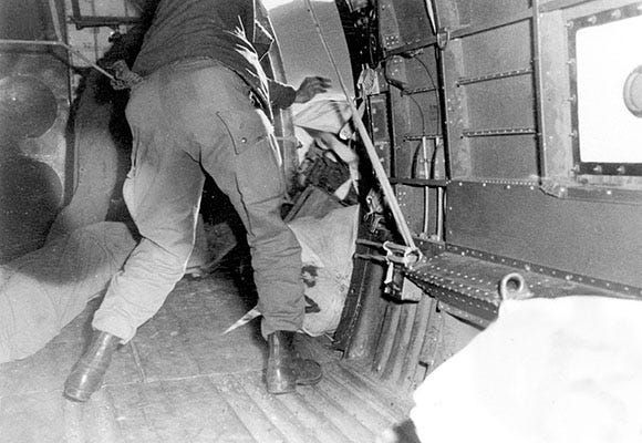 The "kicker-outer" pushes supplies out of an aircraft door over Burma, 1944–45. Image courtesy of the Office of the Command Historian. 