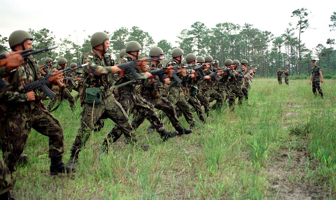 Romanian soldiers form a line across the field as they practice riot control procedures during Exercise Cooperative Osprey ’98 on June 6, 1998, at Marine Corps Base, Camp Lejeune, N.C. Cooperative Osprey ’98 is a Partnership for Peace situational training exercise designed to improve the interoperability of NATO and partner nations through the practice of combined peacekeeping and humanitarian relief operations. Partner nations at the time included Albania, Bulgaria, Estonia, Georgia, Kazakstan, Kyrgyzstan, Latvia, Lithuania, Moldova, Poland, Romania, Ukraine, and Uzbekistan. Wikimedia Commons.