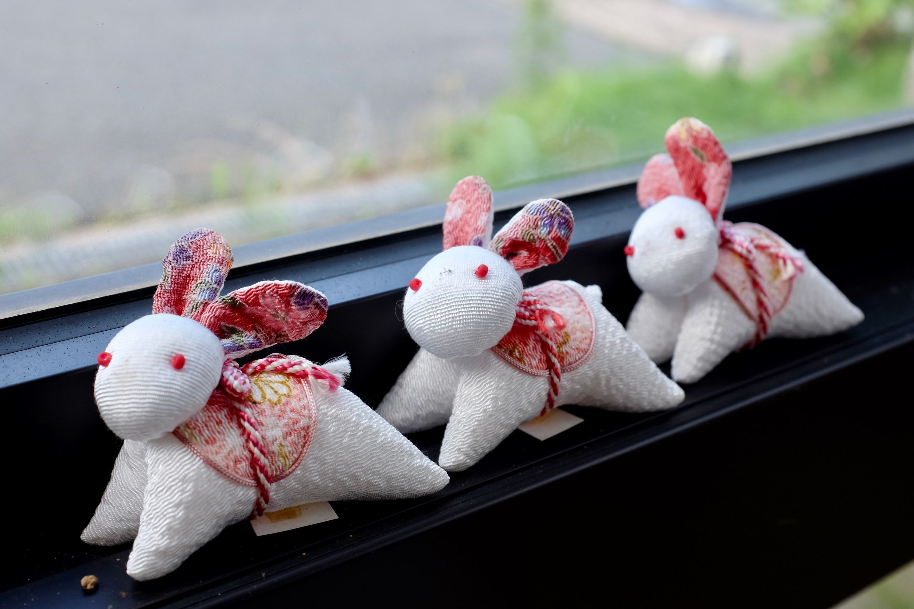 Three white silk rabbits in the window of a shop.