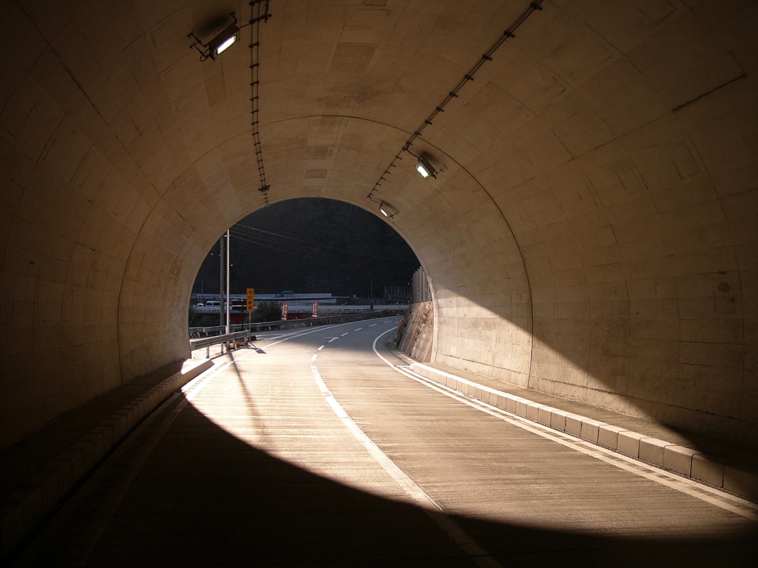 Looking at the sunlit exit of a tunnel from inside the tunnel.