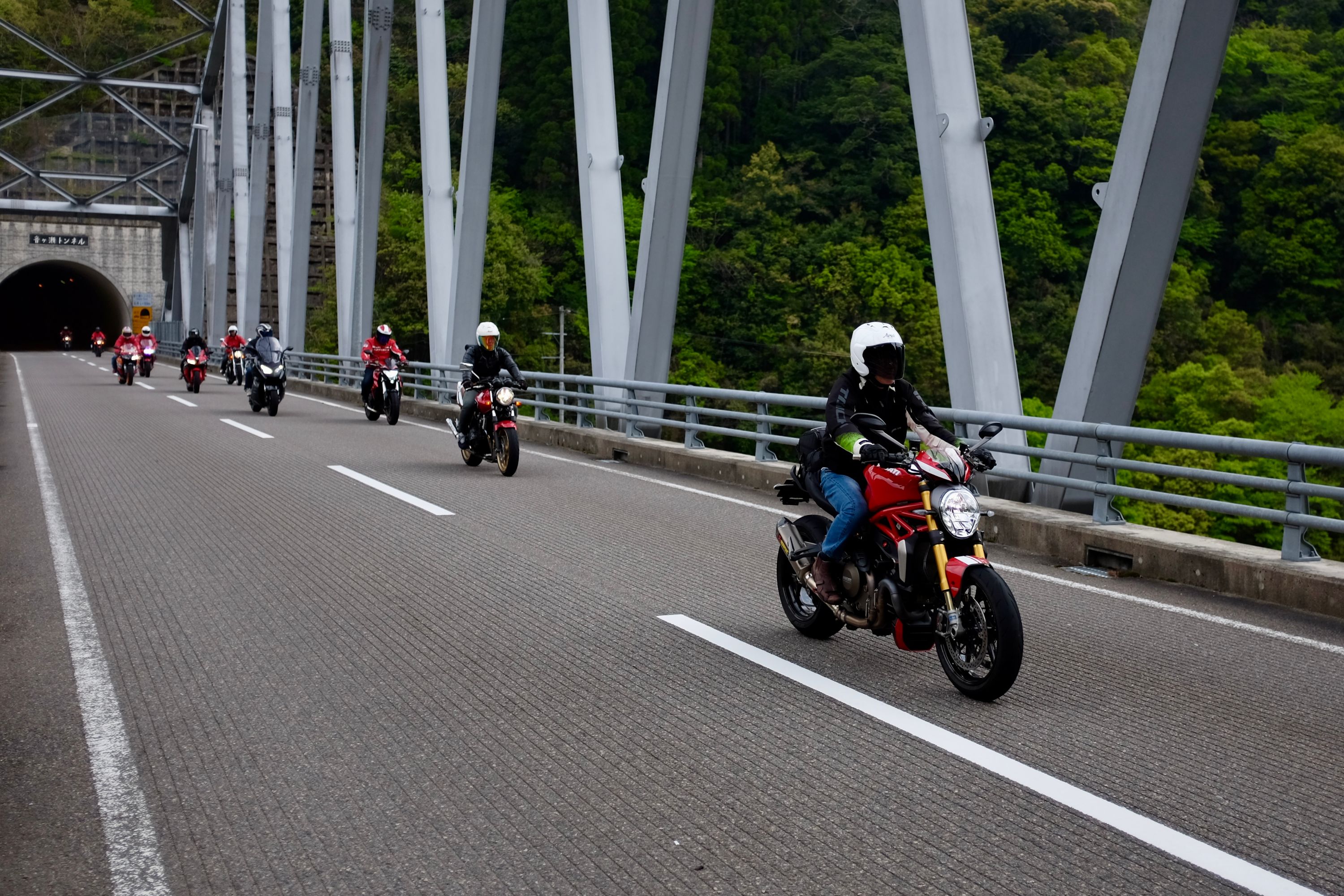 Motorcycles cross a bridge in the mountains.