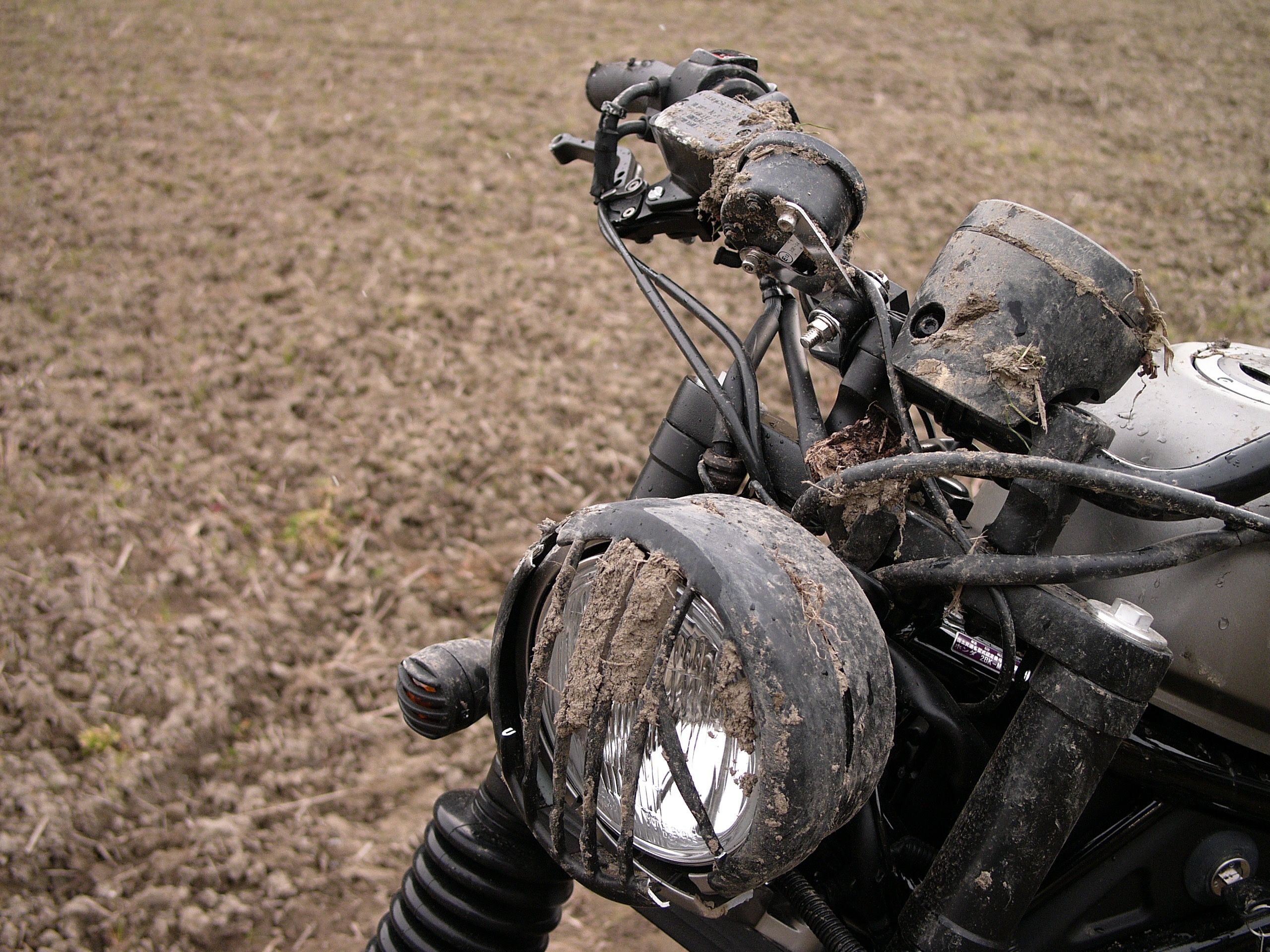 A muddy motorcycle stands in a field.