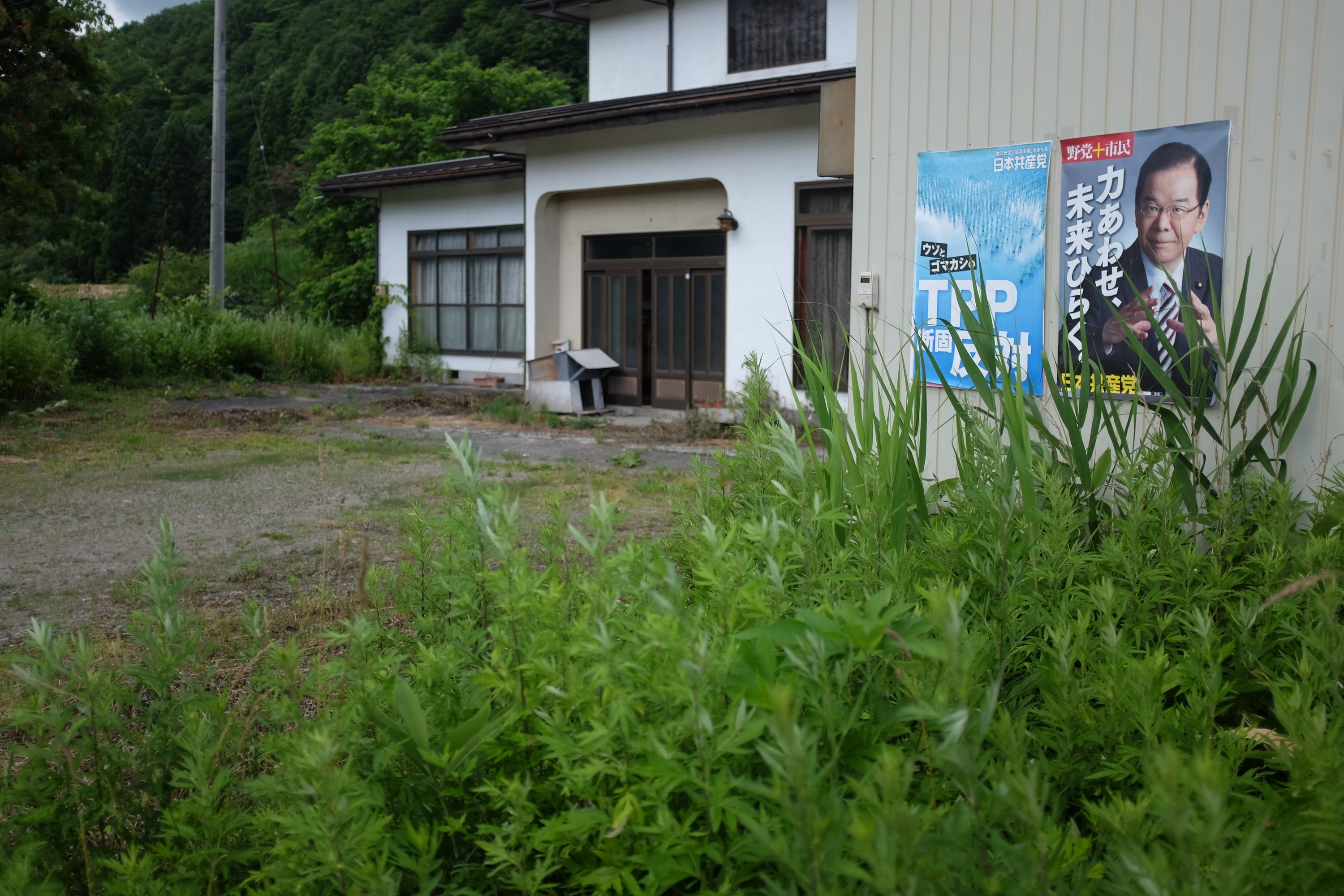 An abandoned-looking house with two political posters on its wall.