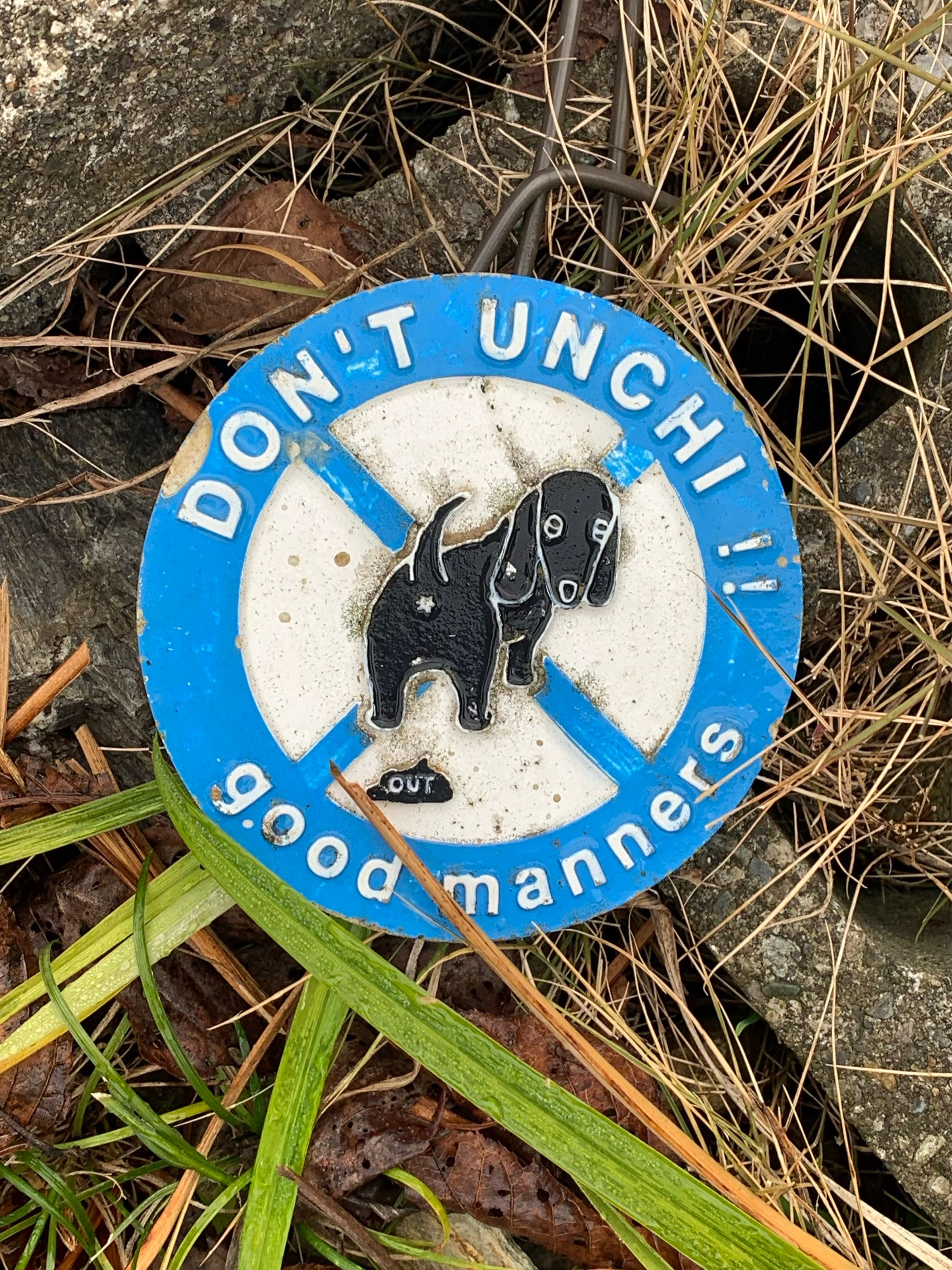 A sign in the grass says: Don’t unchi!! good manners.
