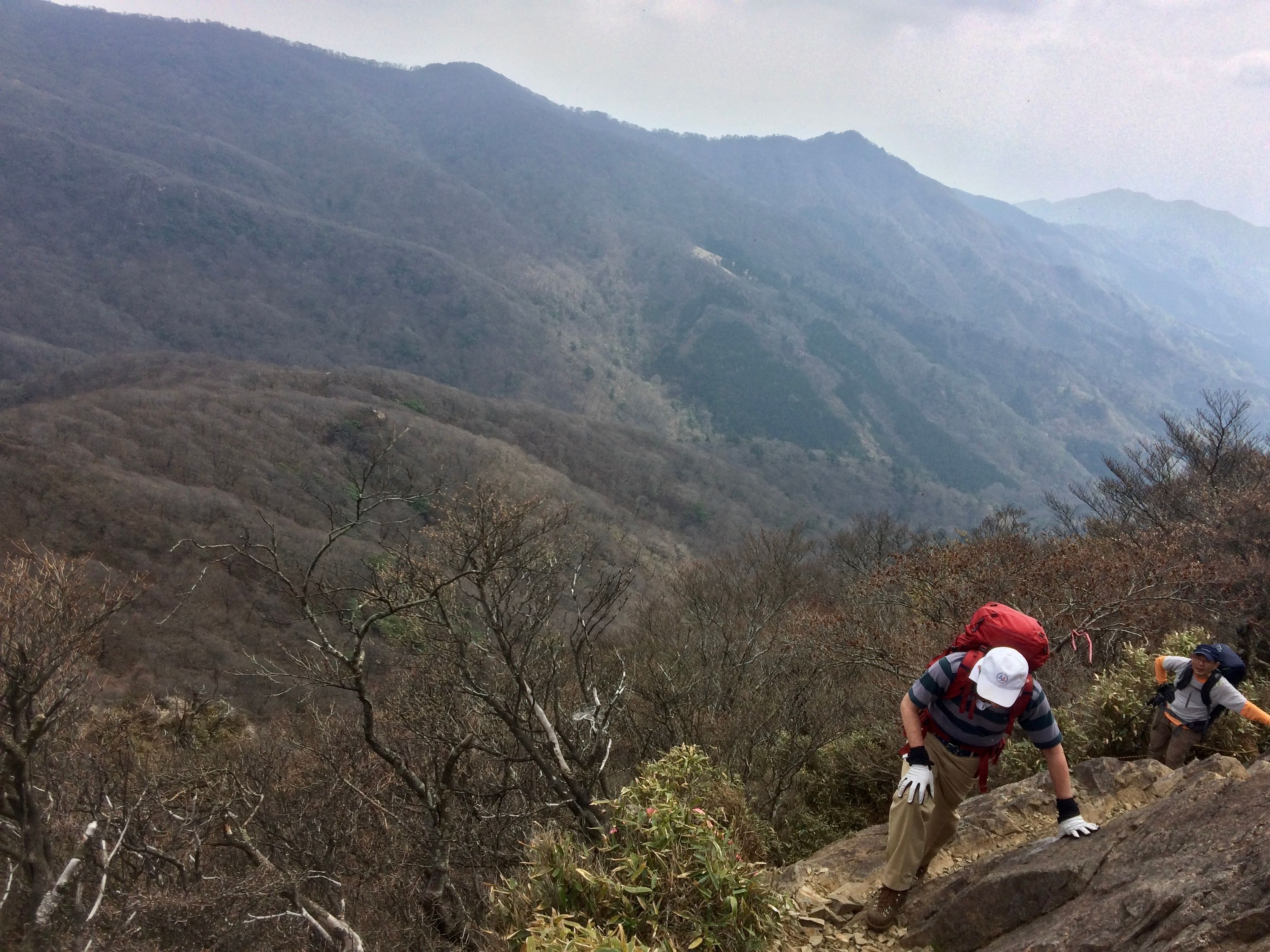 Two men scramble up some rock in the same valley.