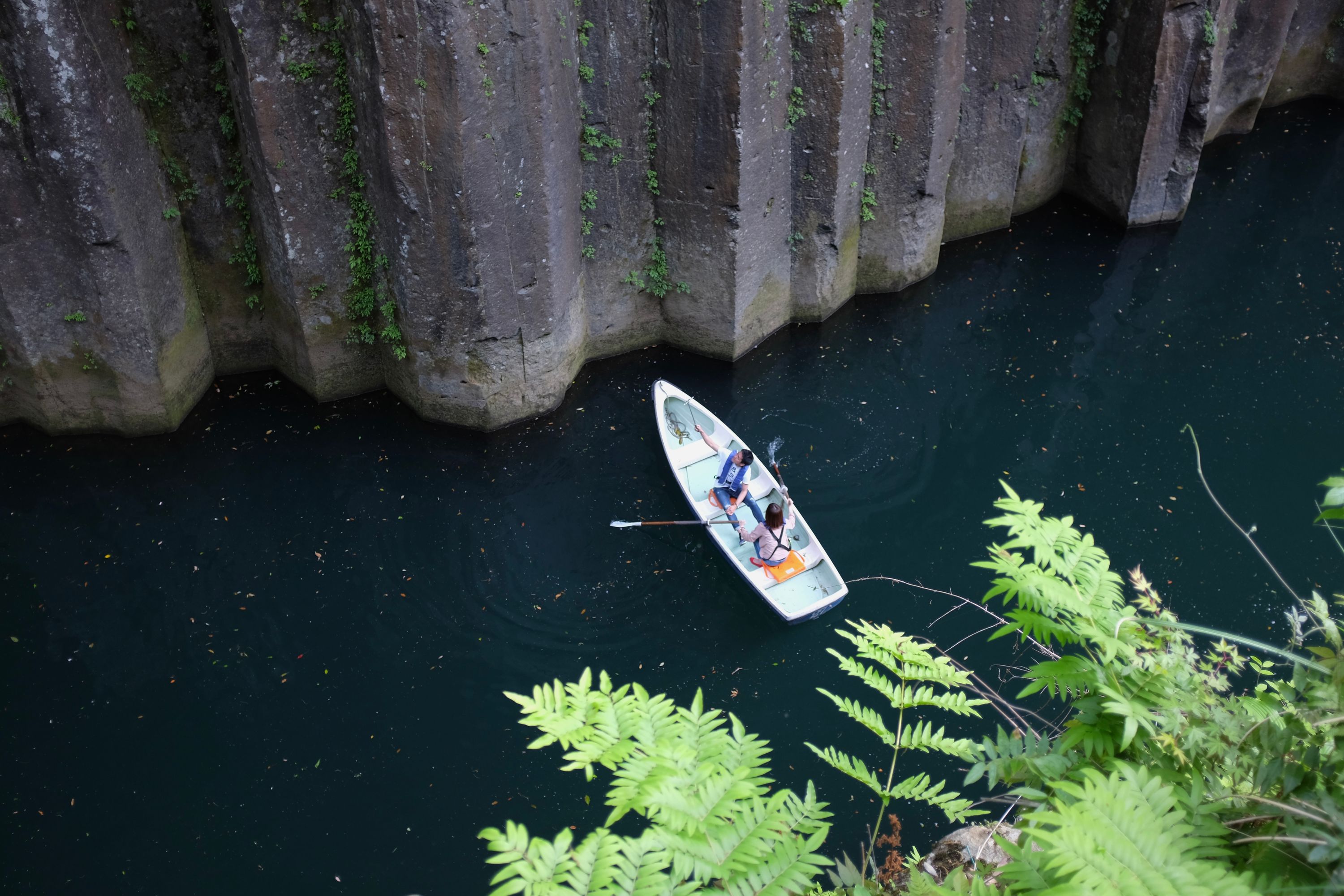 A sightseeing paddle boat in the gorge with two people in it.