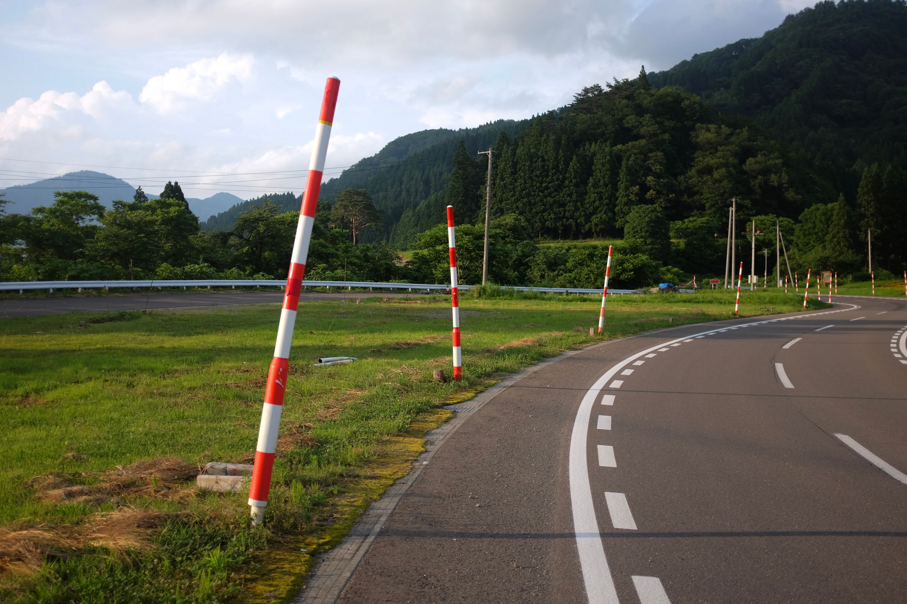 Tall red-white poles mark the edge of a road in the countryside, designed to stick out of the region’s heavy snows in the winter.