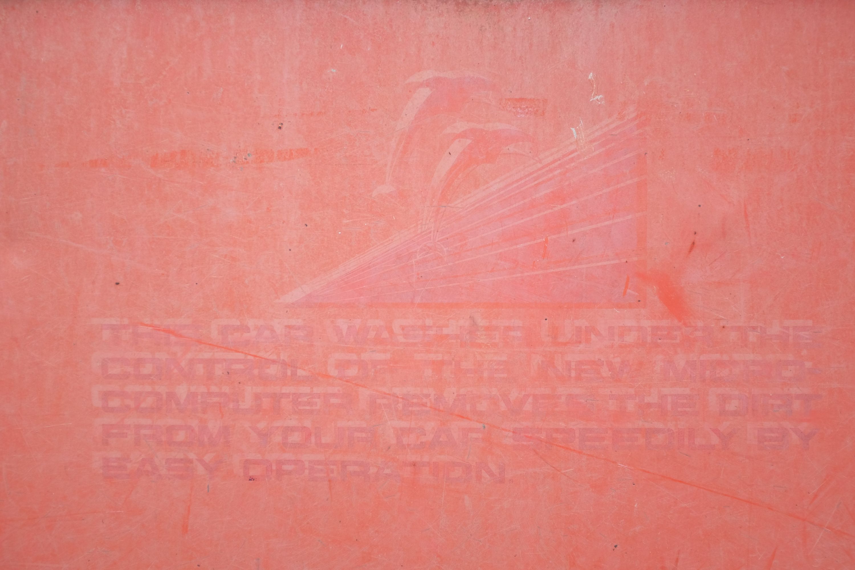 The red sign of a car wash with barely legible, faded English text.