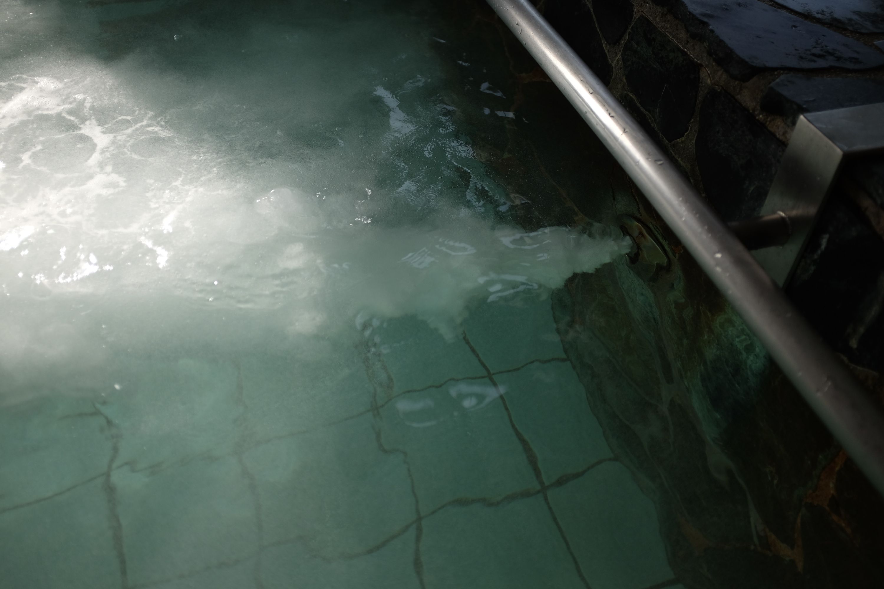 Water gushes into a bathtub from a submerged inlet pipe.