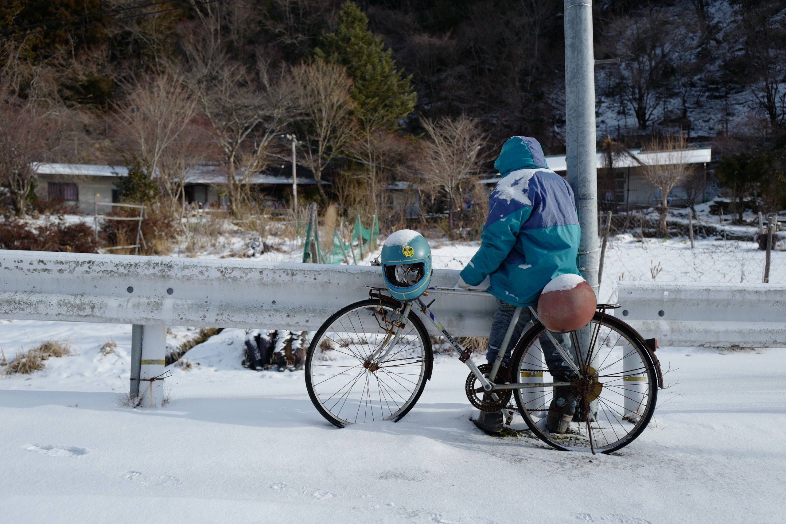 A doll stands by its bicycle in the snow.