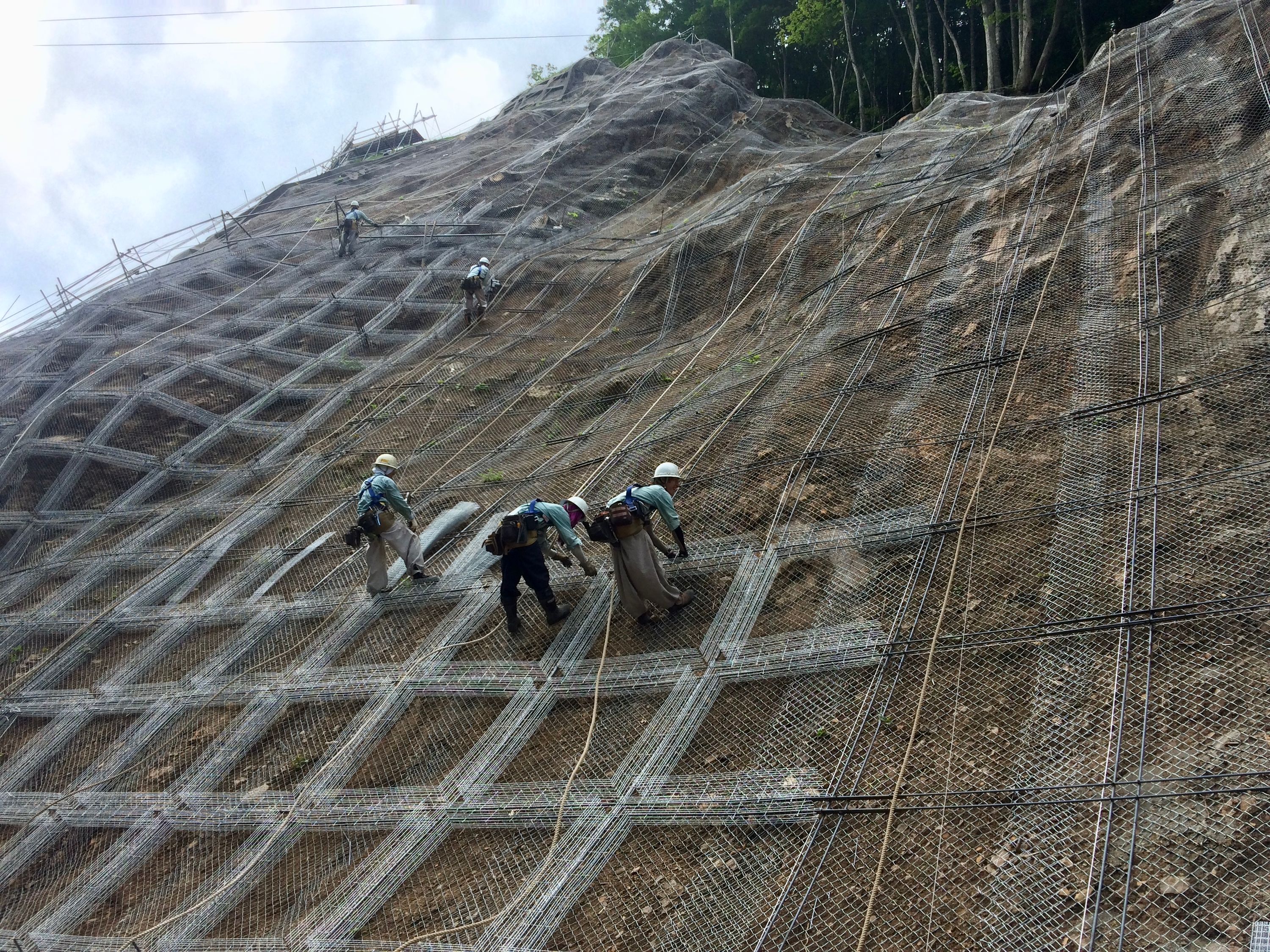 Some of the construction workers building the wall, suspended on cables from above.