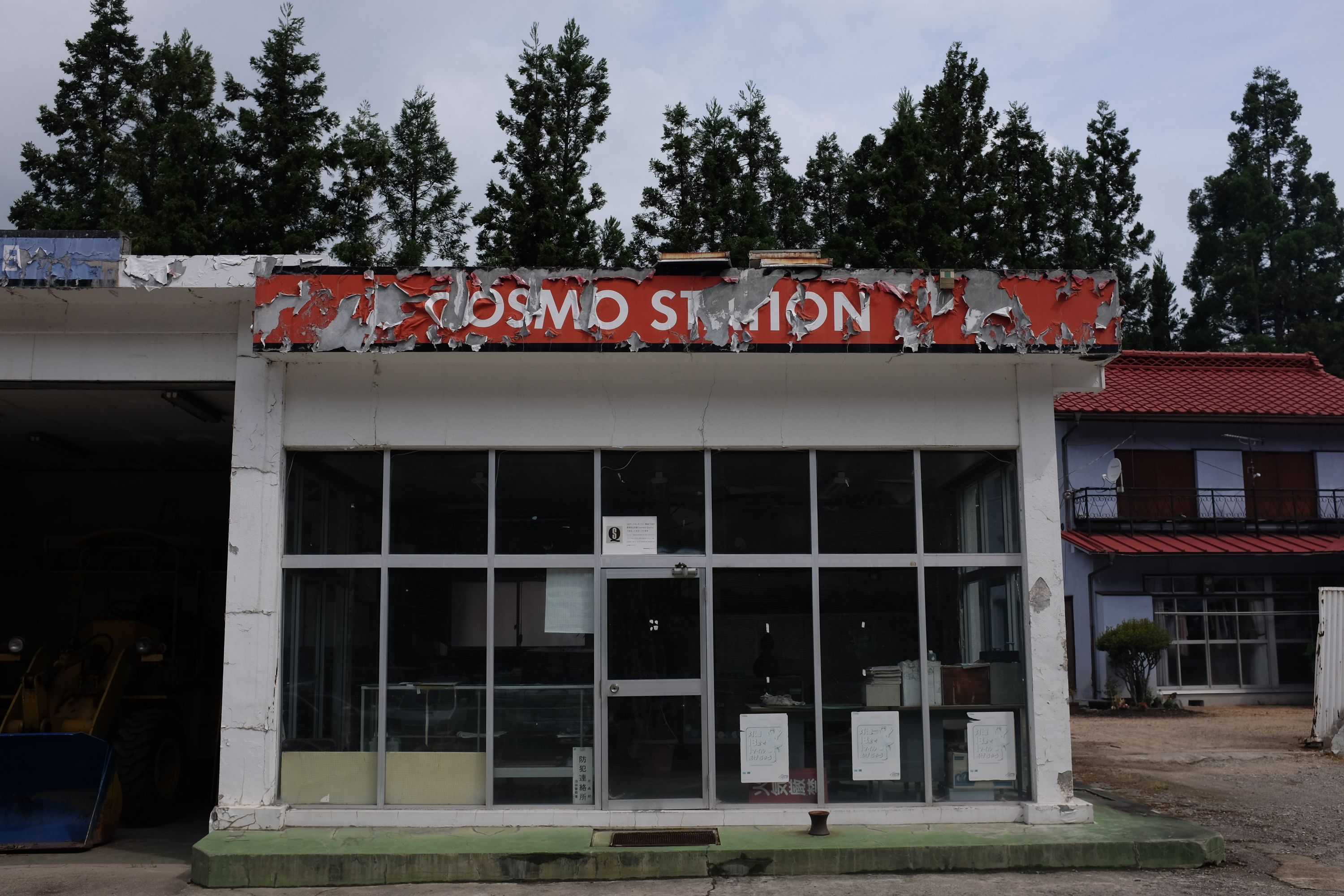 A small building with a peeling sign saying COSMO STATION.