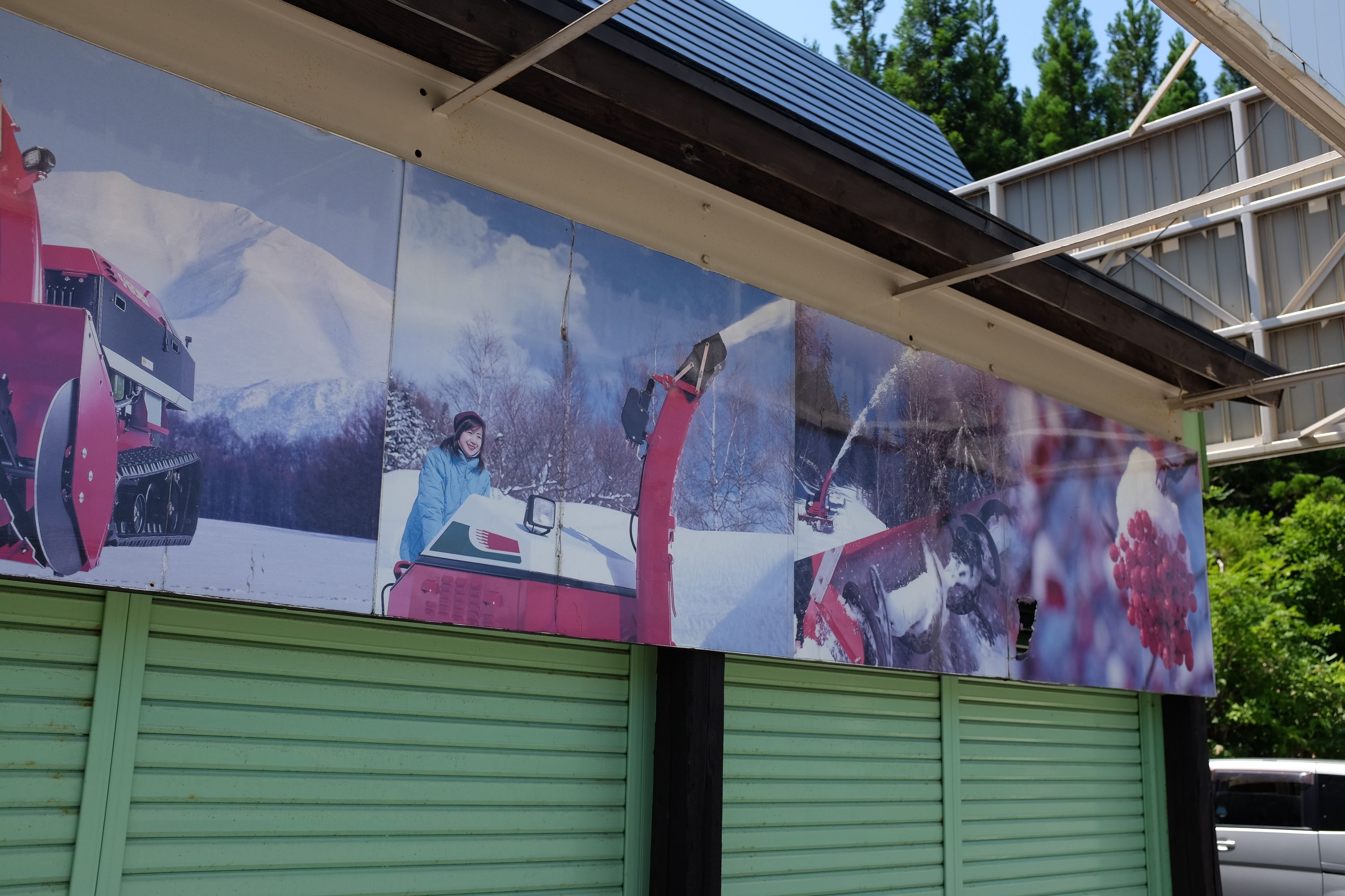 Advertisements for snowplows on a garage door, showing an enthusiastic woman in a blue coat in a snowy landscape.