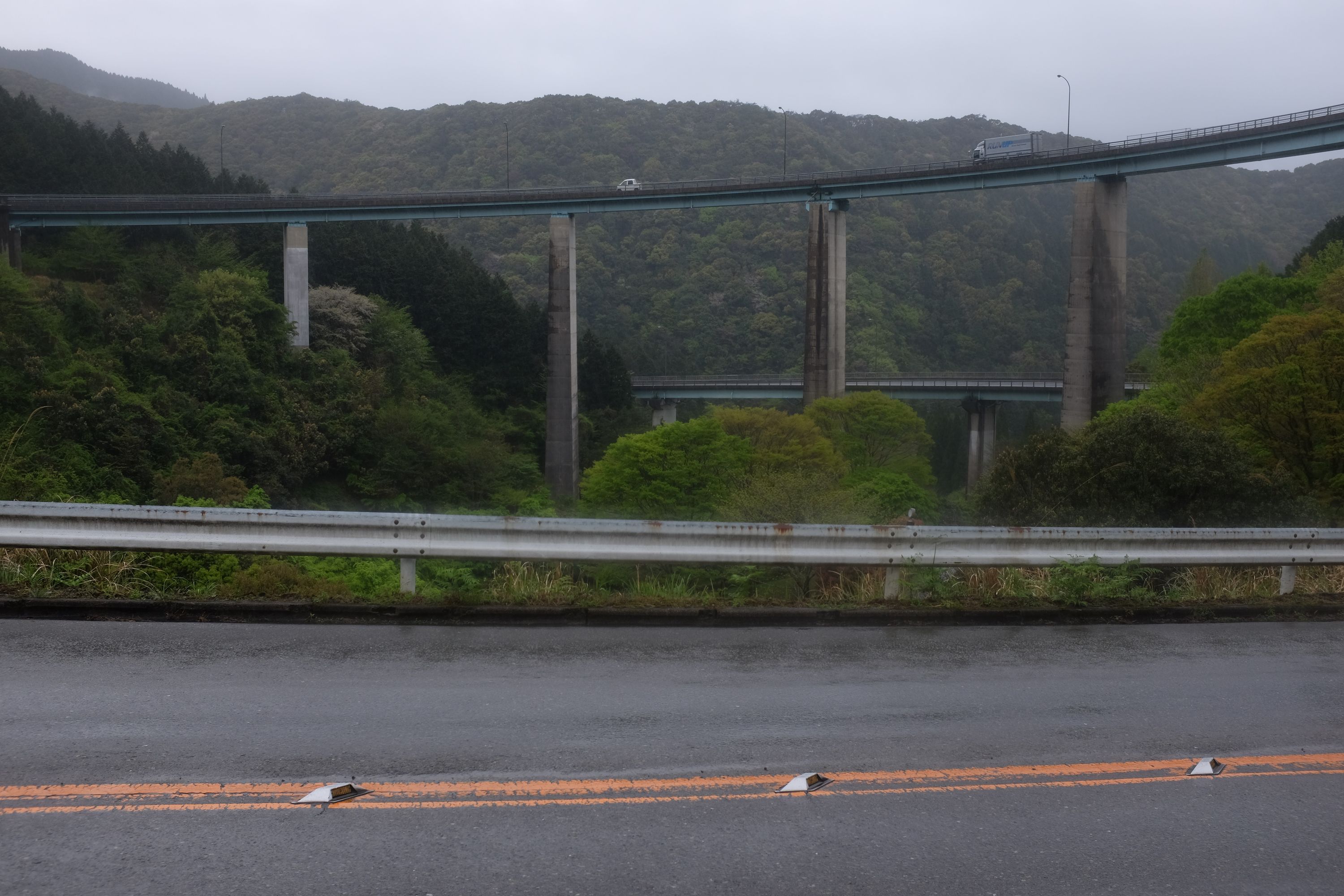 Several high roads criss-cross above wet, forested hills.