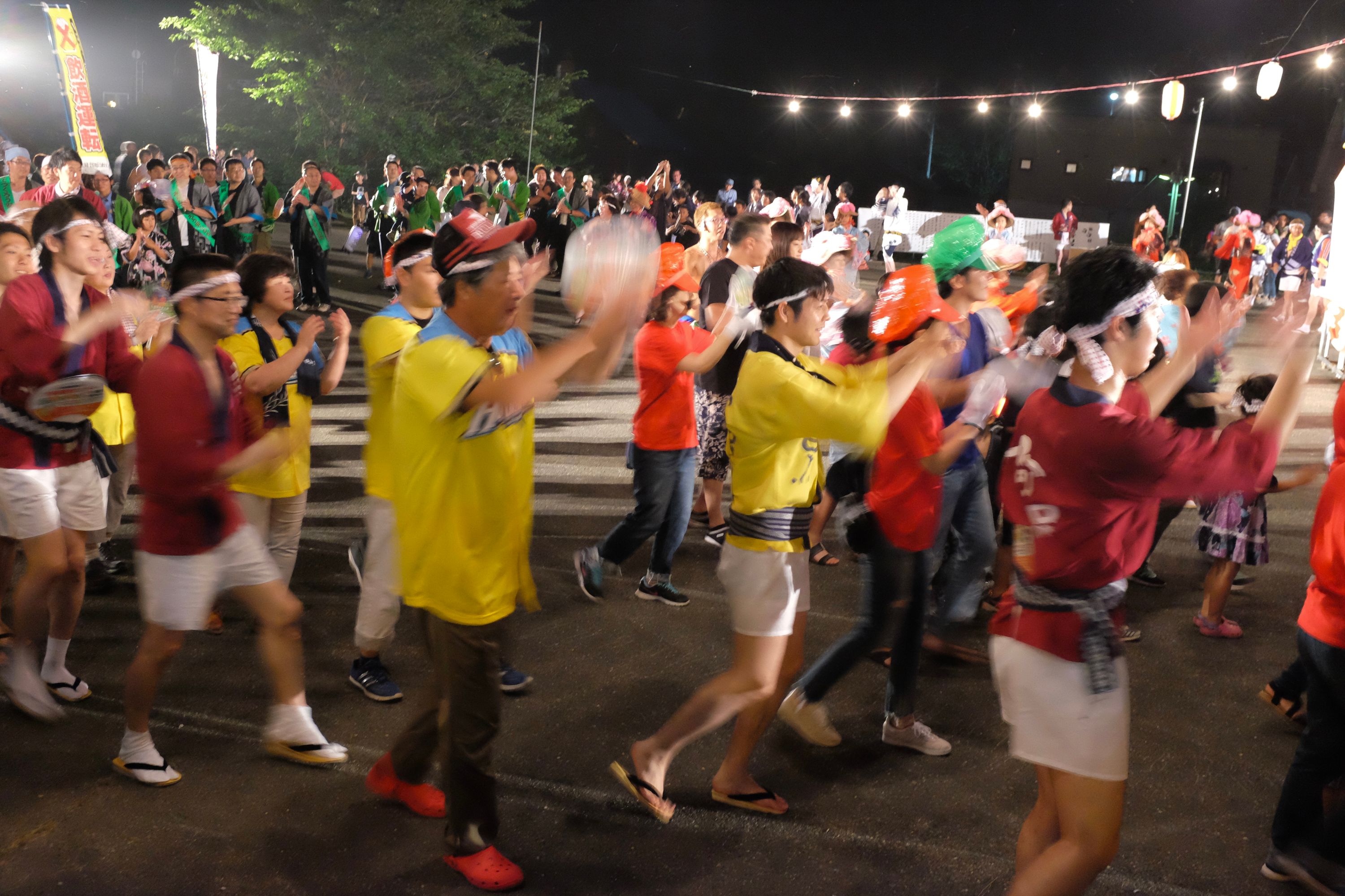 Groups of people in festival uniforms dancing at night.