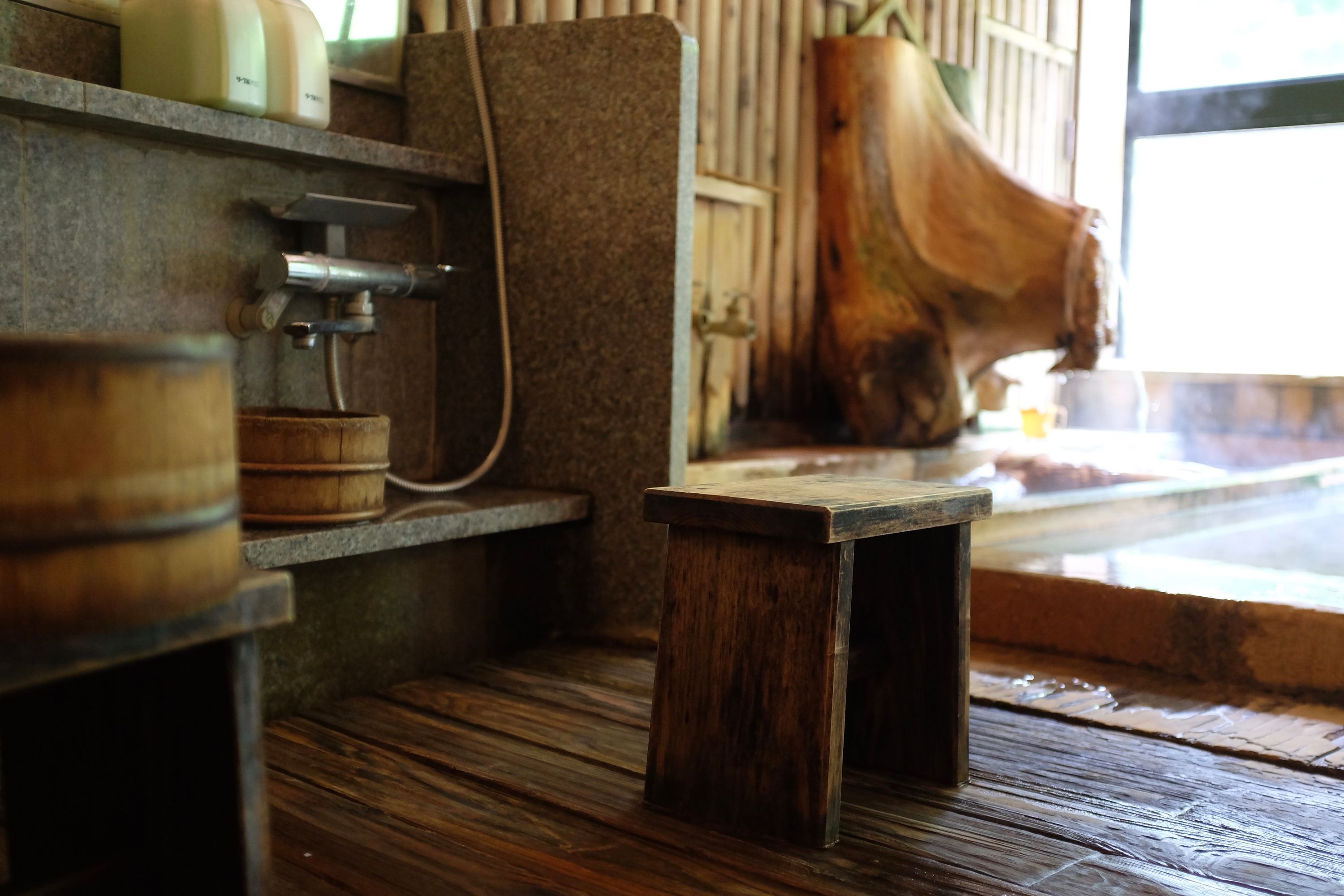 A ground-level view of stools and washtubs inside an old bathhouse.