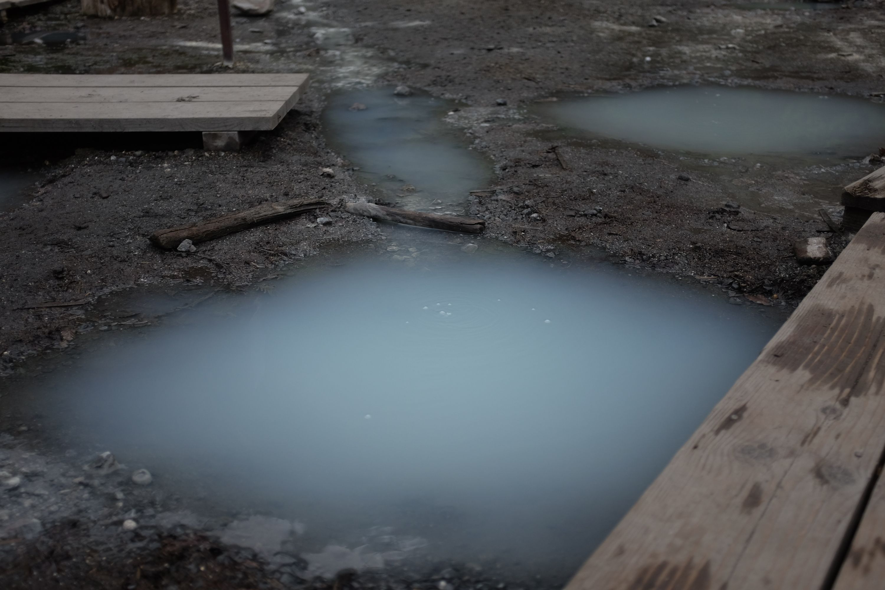 Blue-gray mineral water bubbles up from the ground and forms a small pool.
