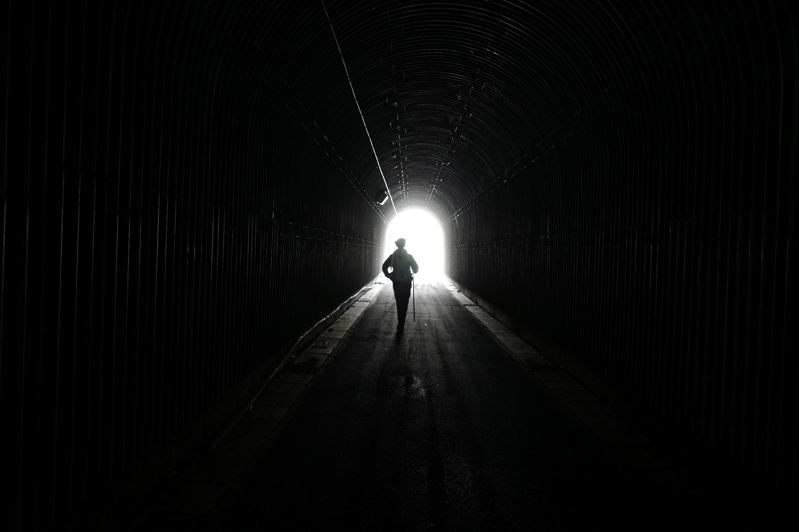 The silhouette of a man with a walking stick, the author, walking through a tunnel.