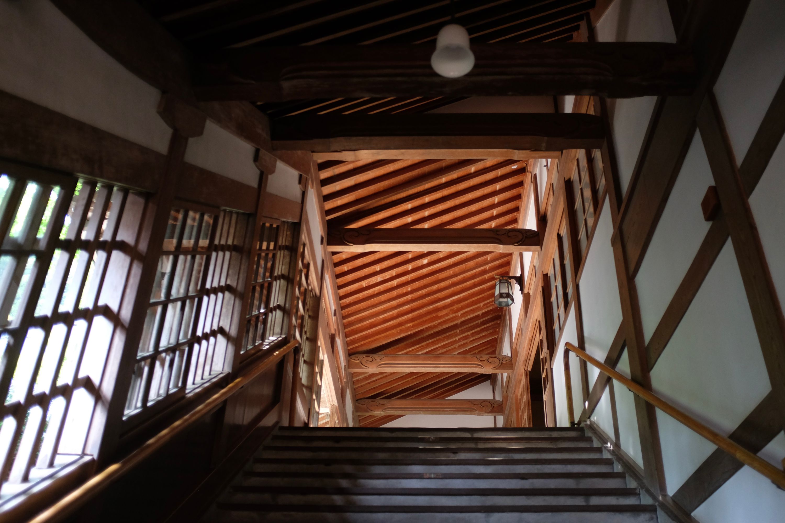 A carved wooden hallway with windows on the left.