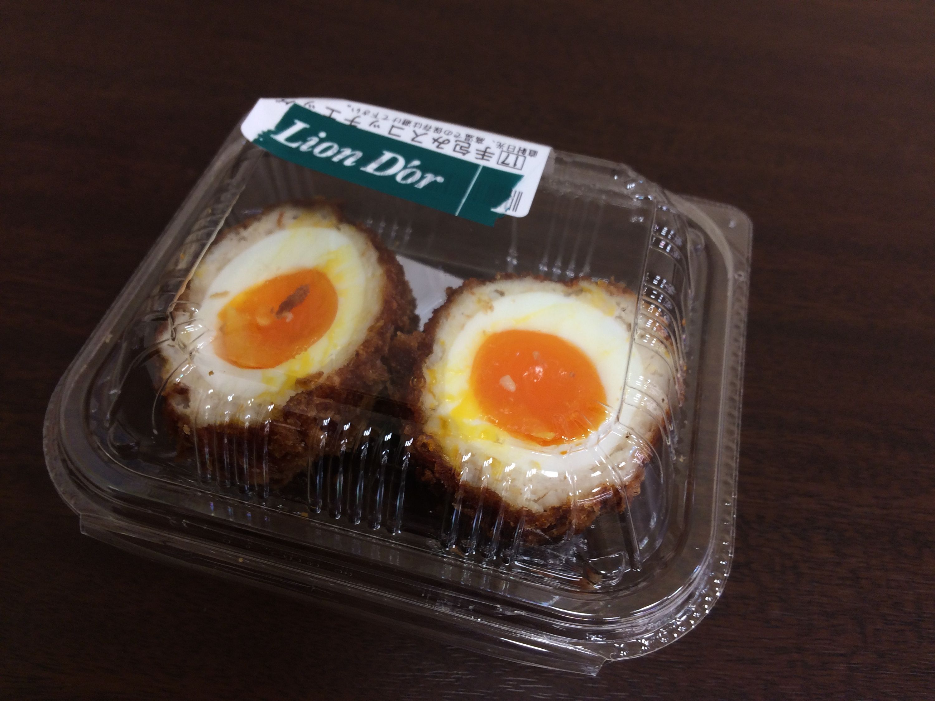 A Scotch egg in a clear plastic box.
