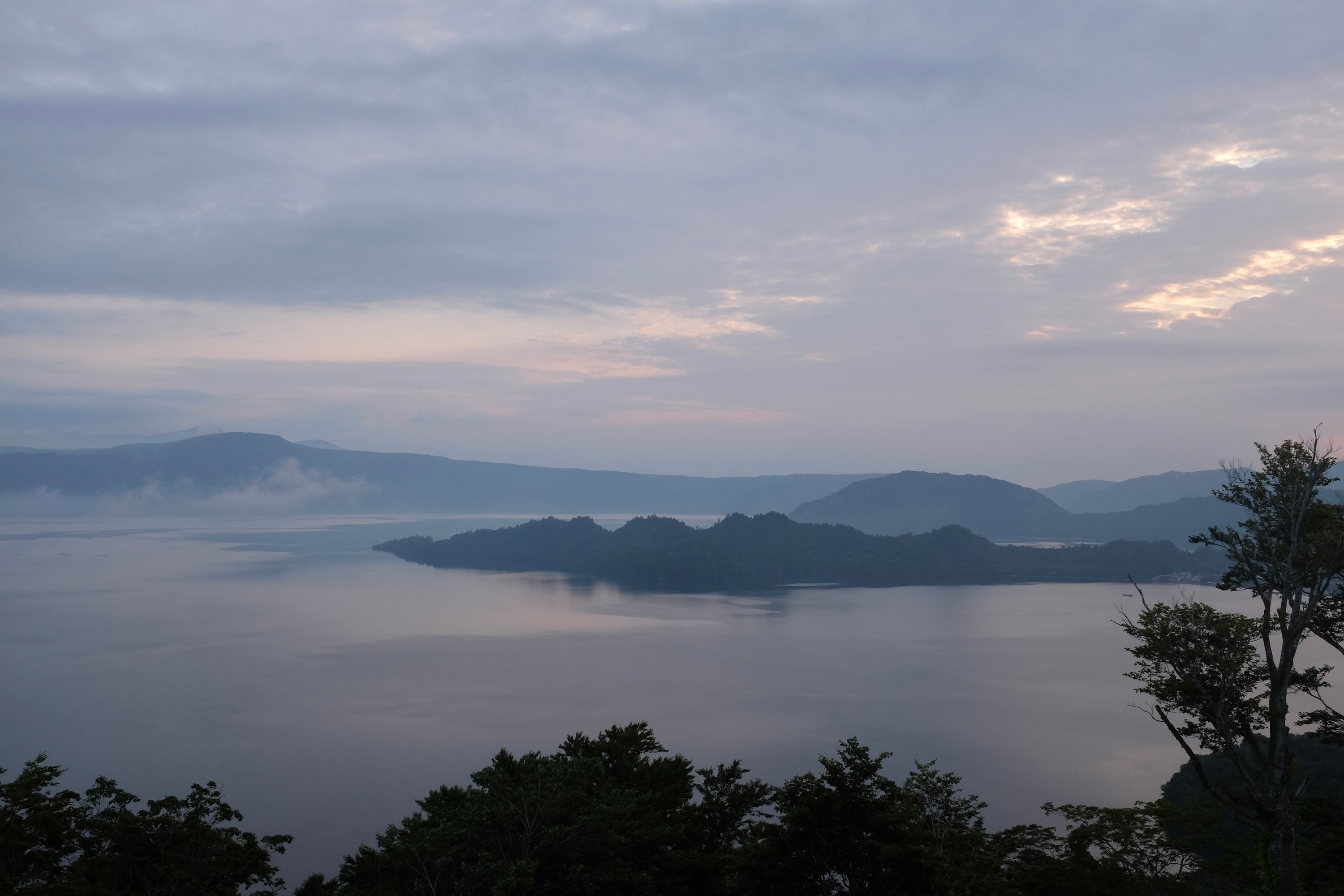 The pastel tones of early morning light across a very large lake.