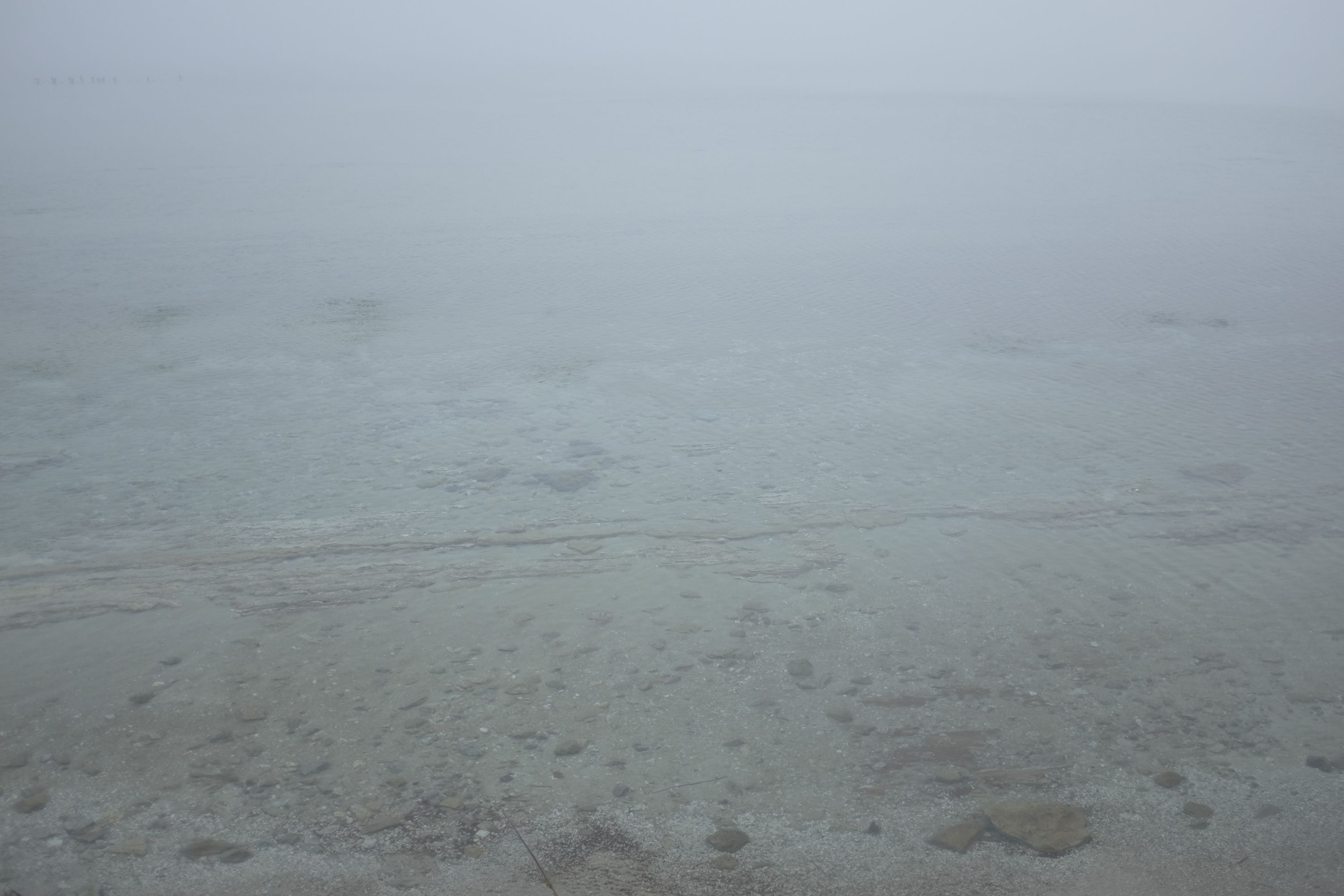 The light grey waters of a lake barely distinguisable from the air.