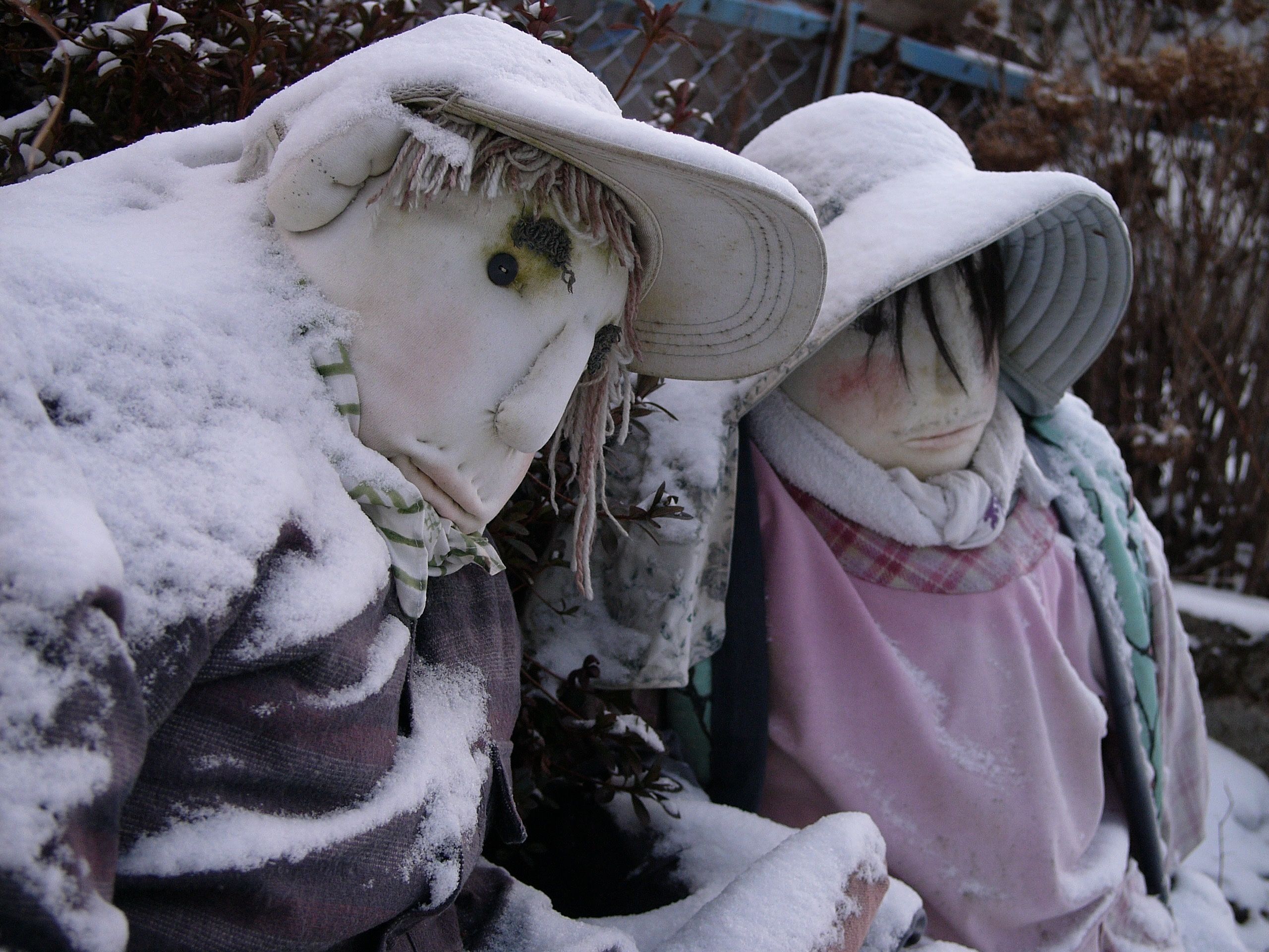 Dolls representing an older man and a woman, similarly covered in snow.