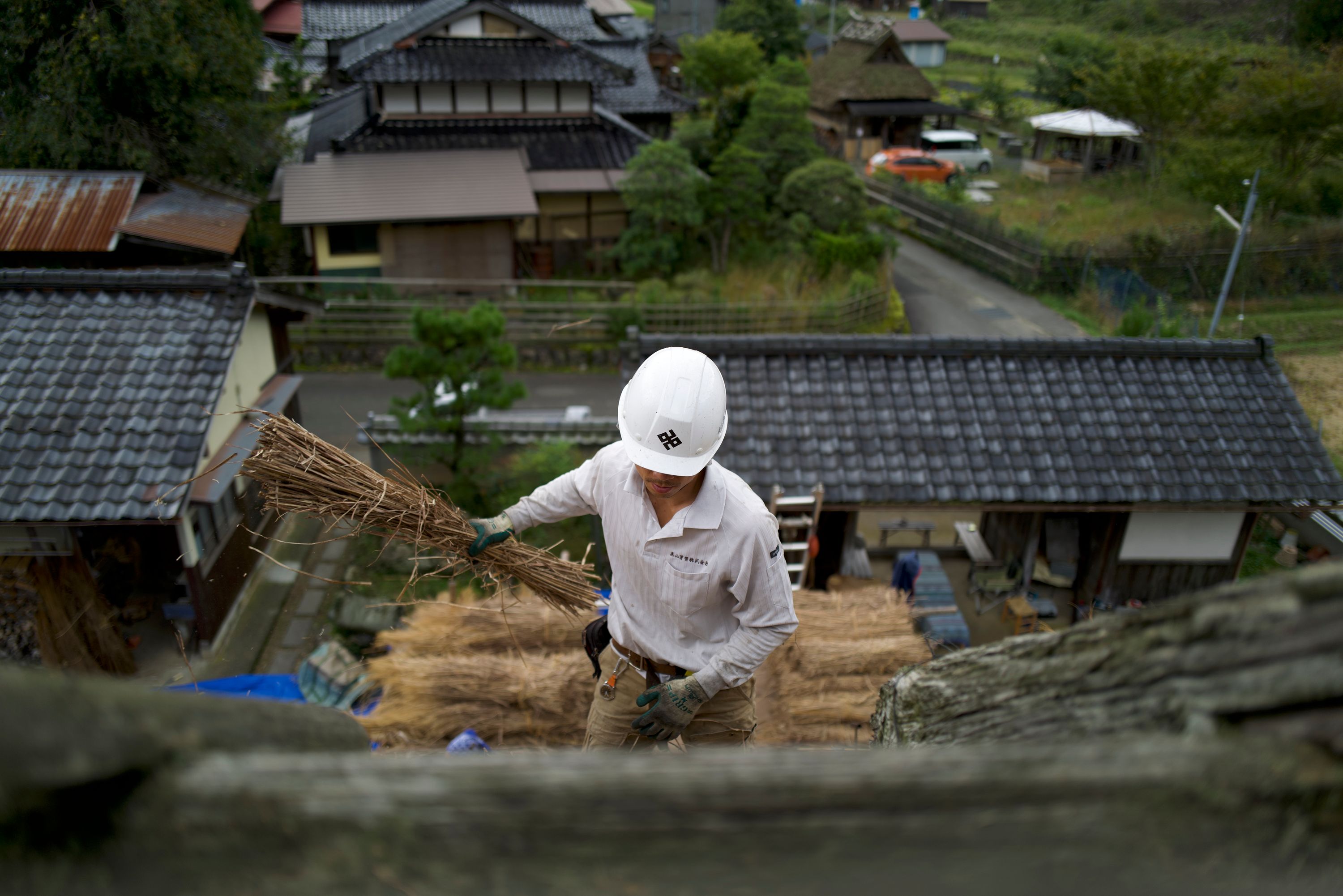 A thatcher works on the roof of a traditional Japanese house.