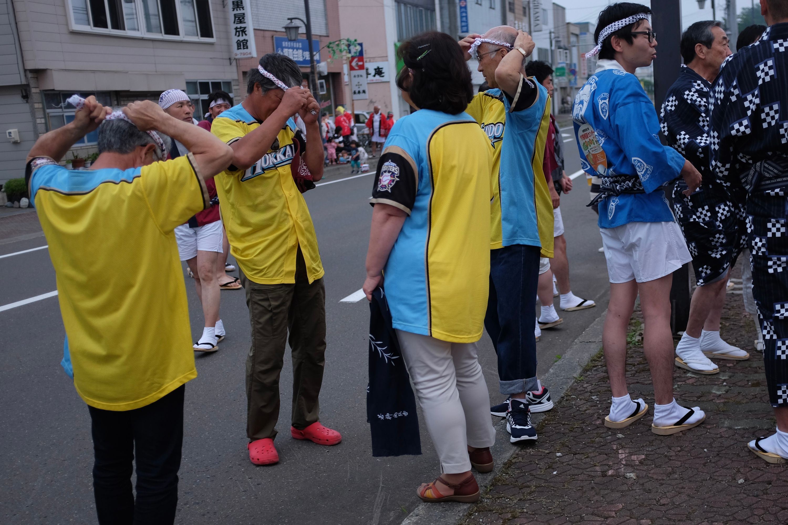 A group of men adjust their headbands in preparation for a Japanese summer festival.