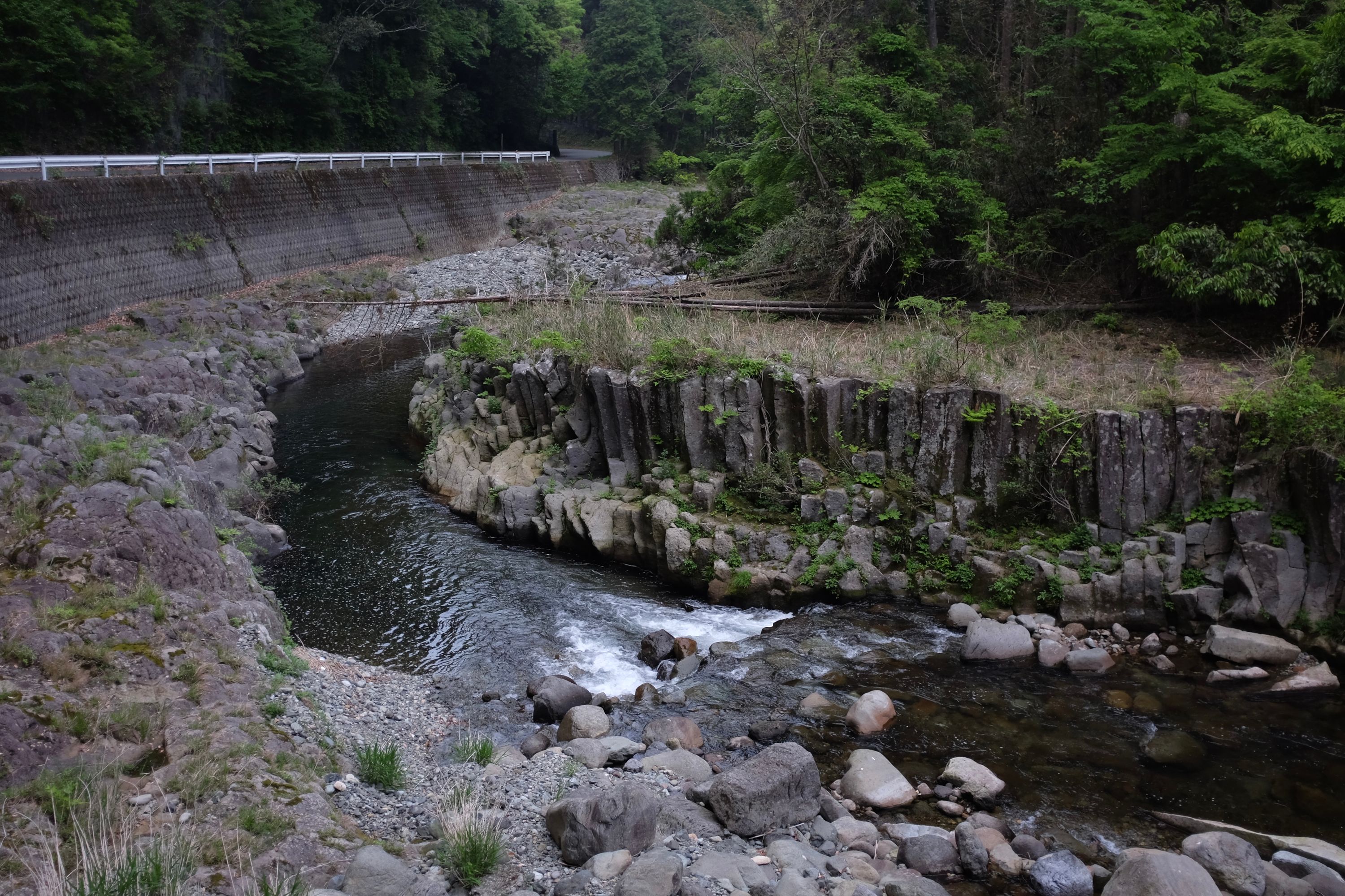 A stream, its banks columns of basalt, flows by a road.