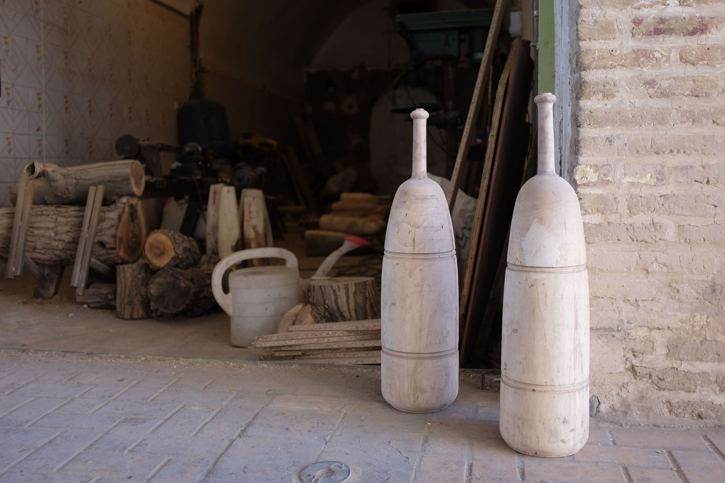 Two large, carved wooden clubs at the entrance of a woodworking shop.