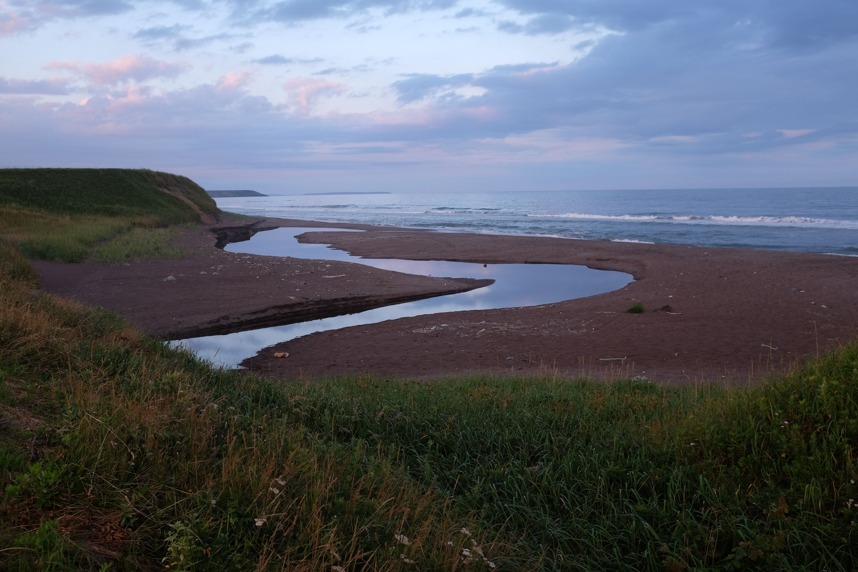 A small stream snakes into the ocean across the beach.