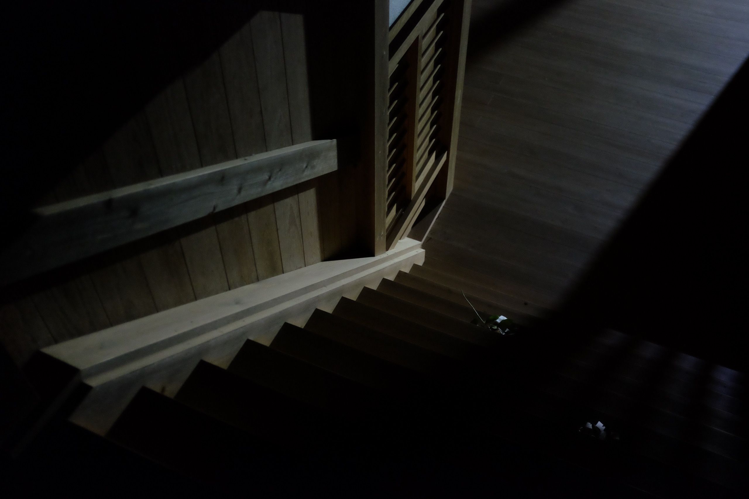 The polished wooden steps and floor of a Japanese shrine in the darkness.