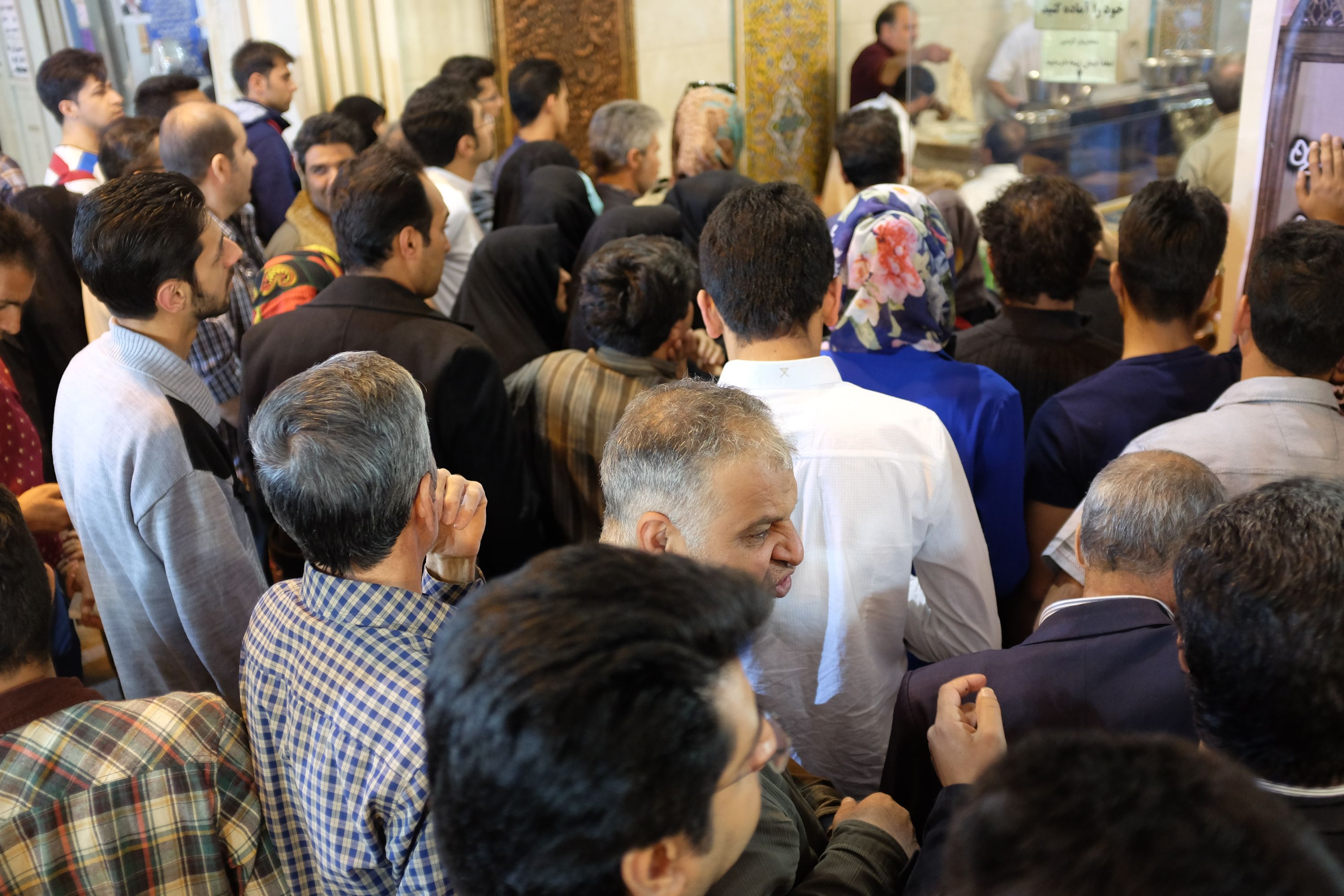 A lot of people throng the door of a restaurant.