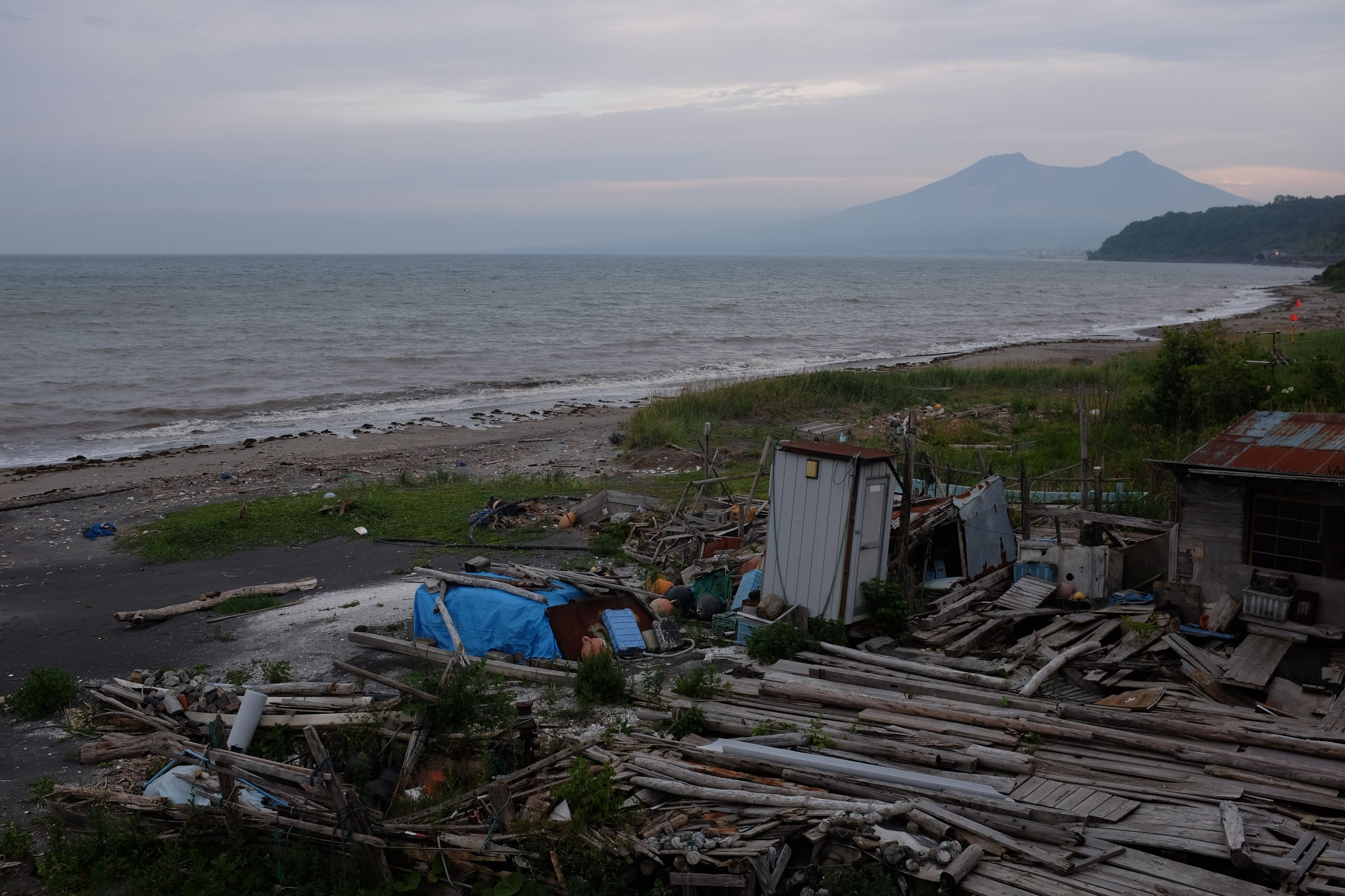 A distant view of Mount Komagatake from a debris-covered beach.