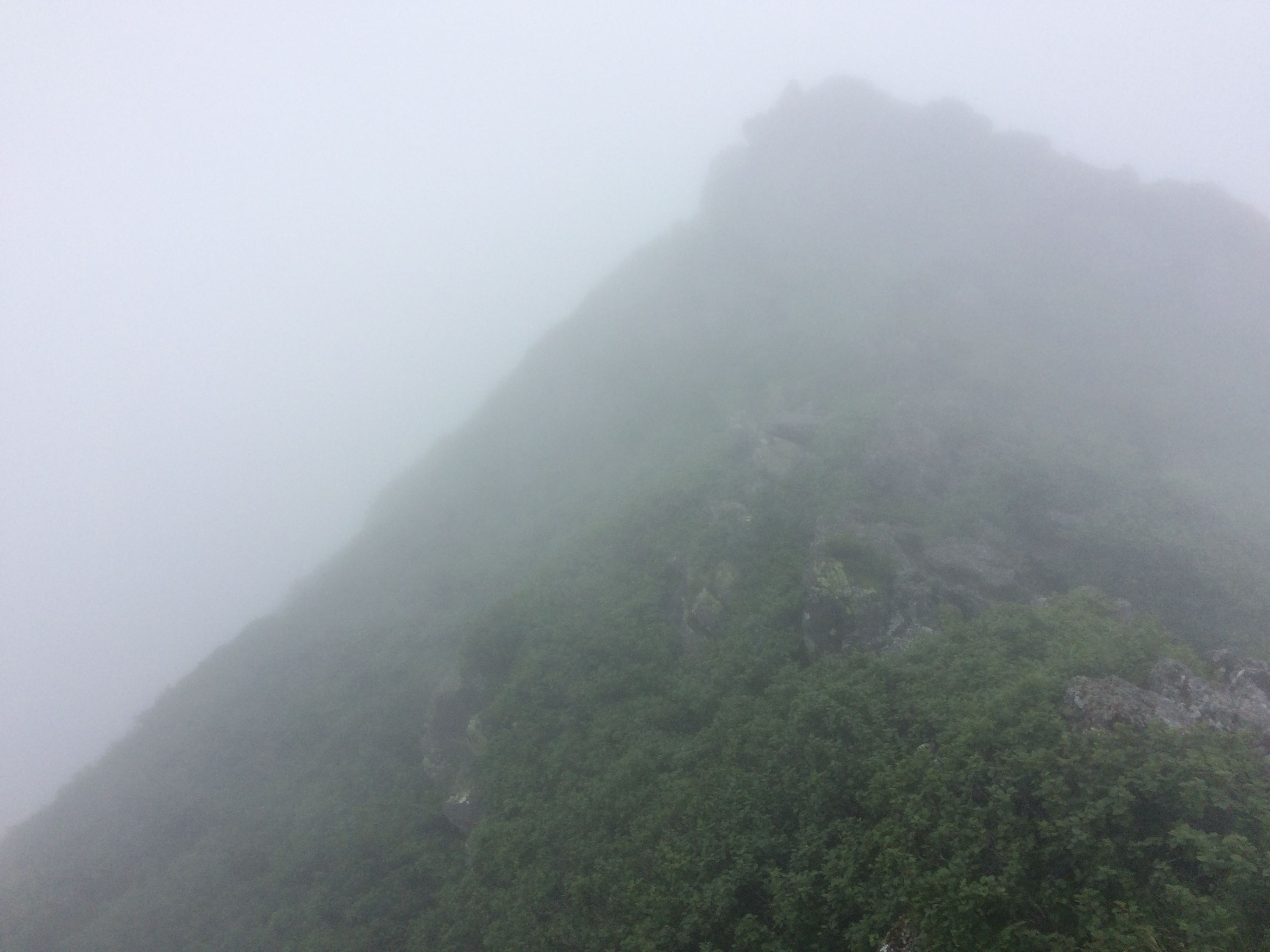 A jagged crater rim barely visible through the clouds.